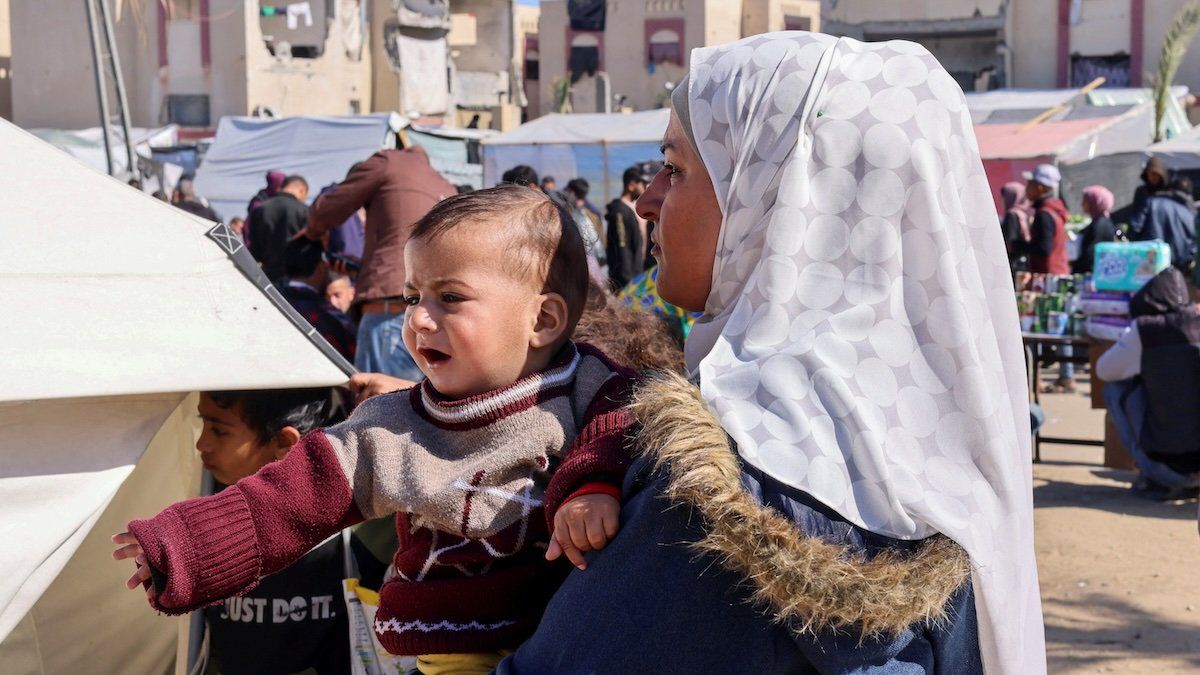 ​A displaced Palestinian woman holds her son outside of a medical tent in Rafah, February 11, 2024.