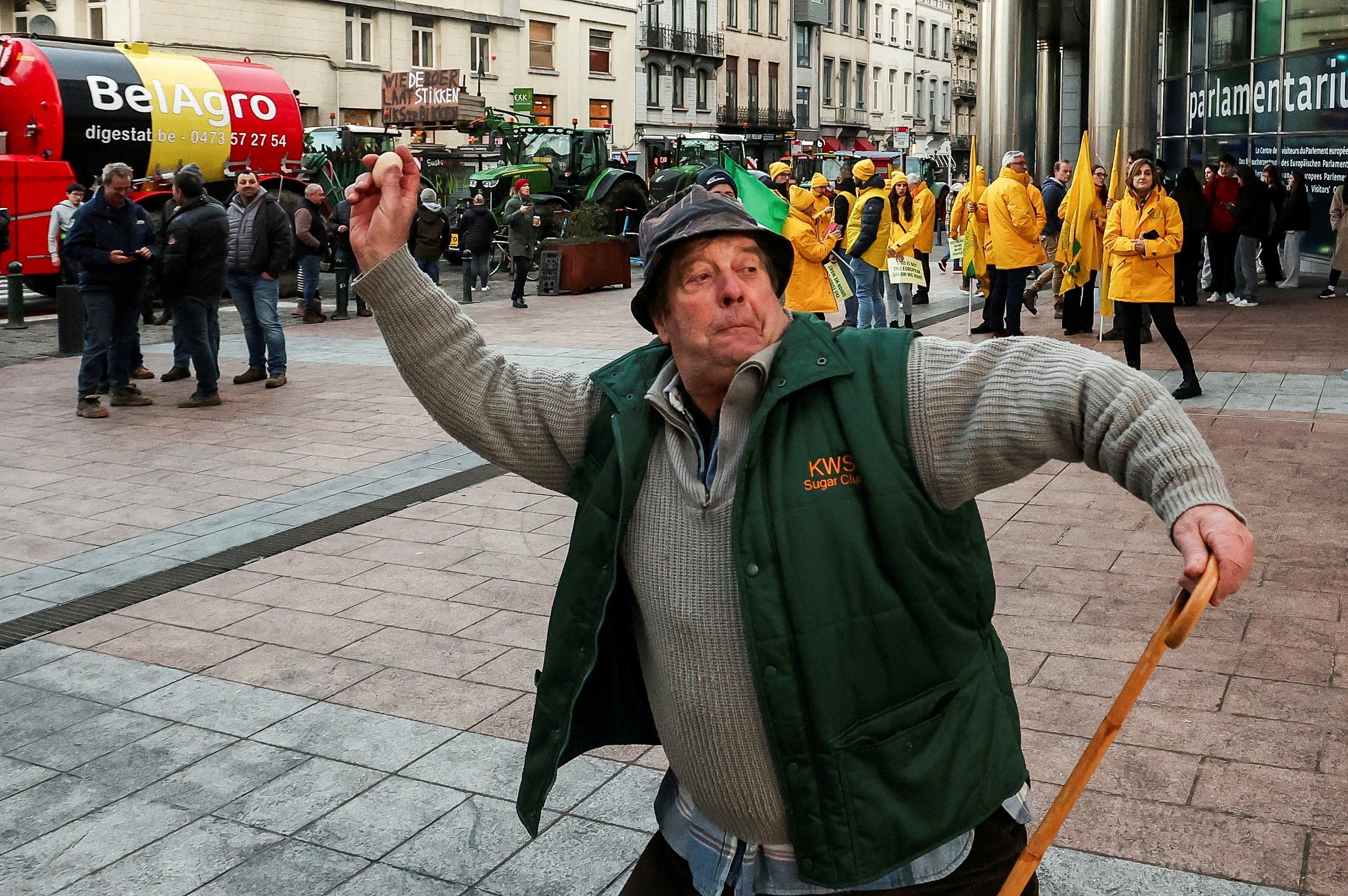 A farmer throws an egg aimed at police officers outside the European Parliament.​