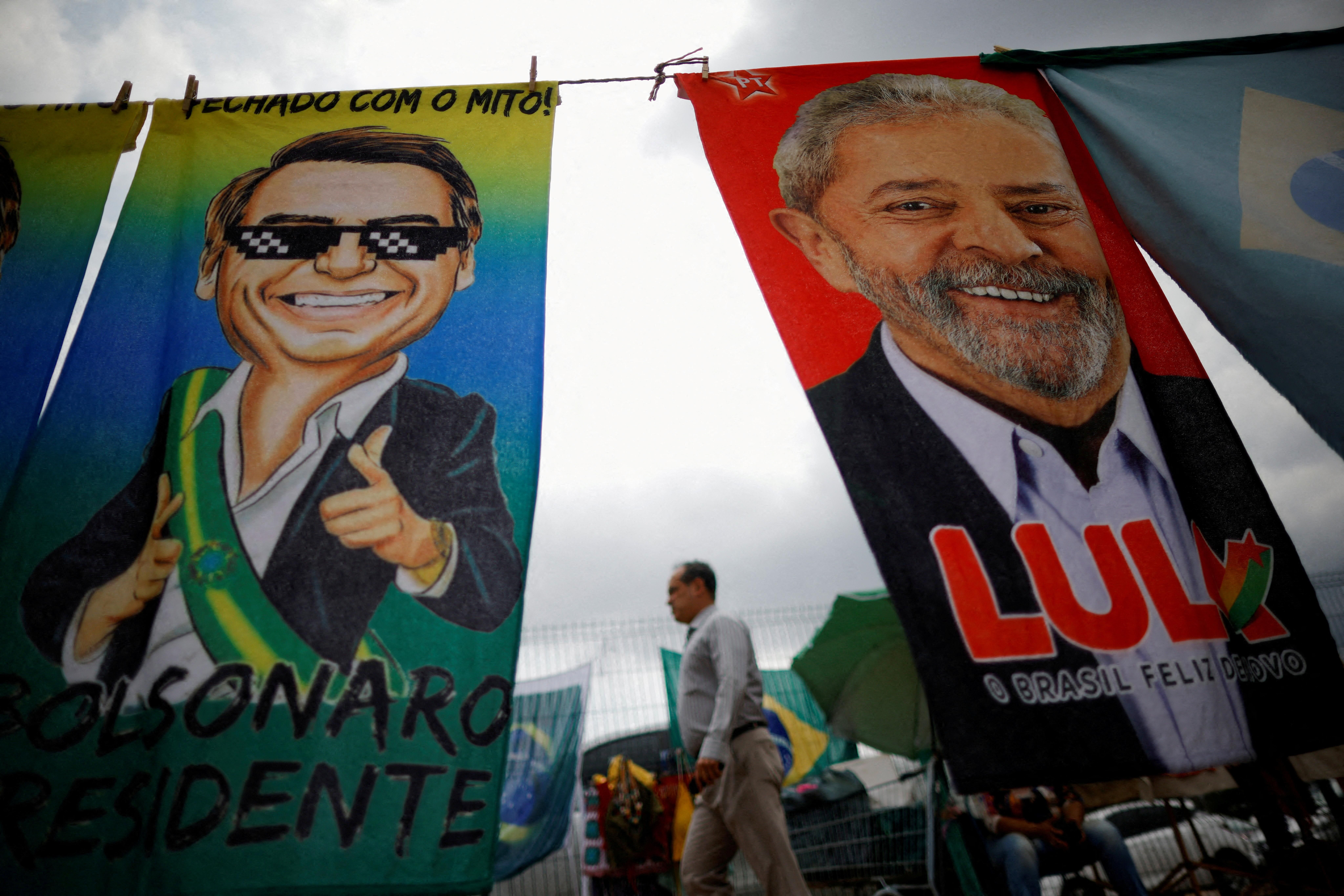 A man walks past Brazilian presidential campaign materials showing candidates Lula and Bolsonaro in Brasilia.