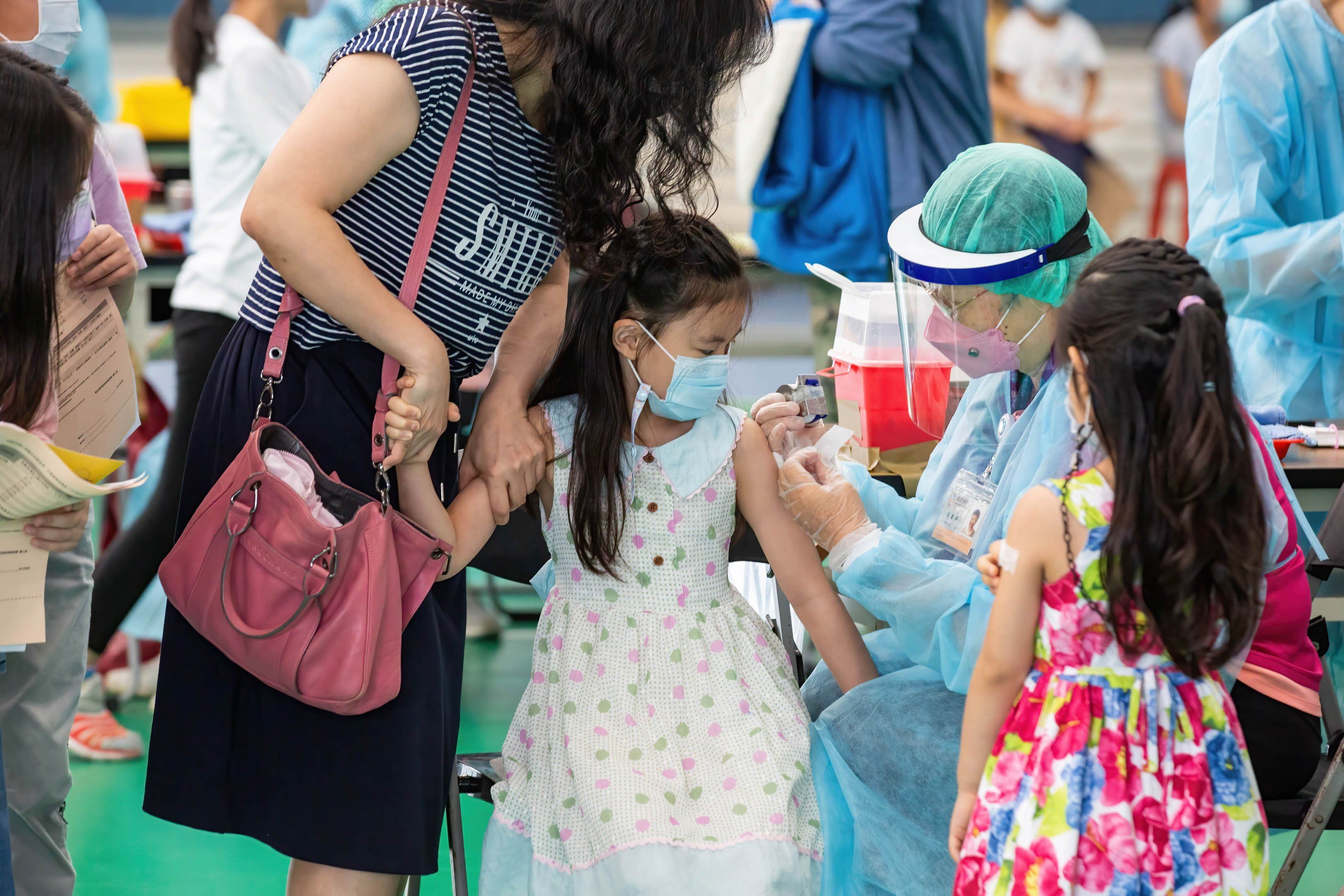 A mother holds her daughter's arm as a healthcare worker administers the child with Pfizer-BNT covid-19 vaccine in Taiwan. 