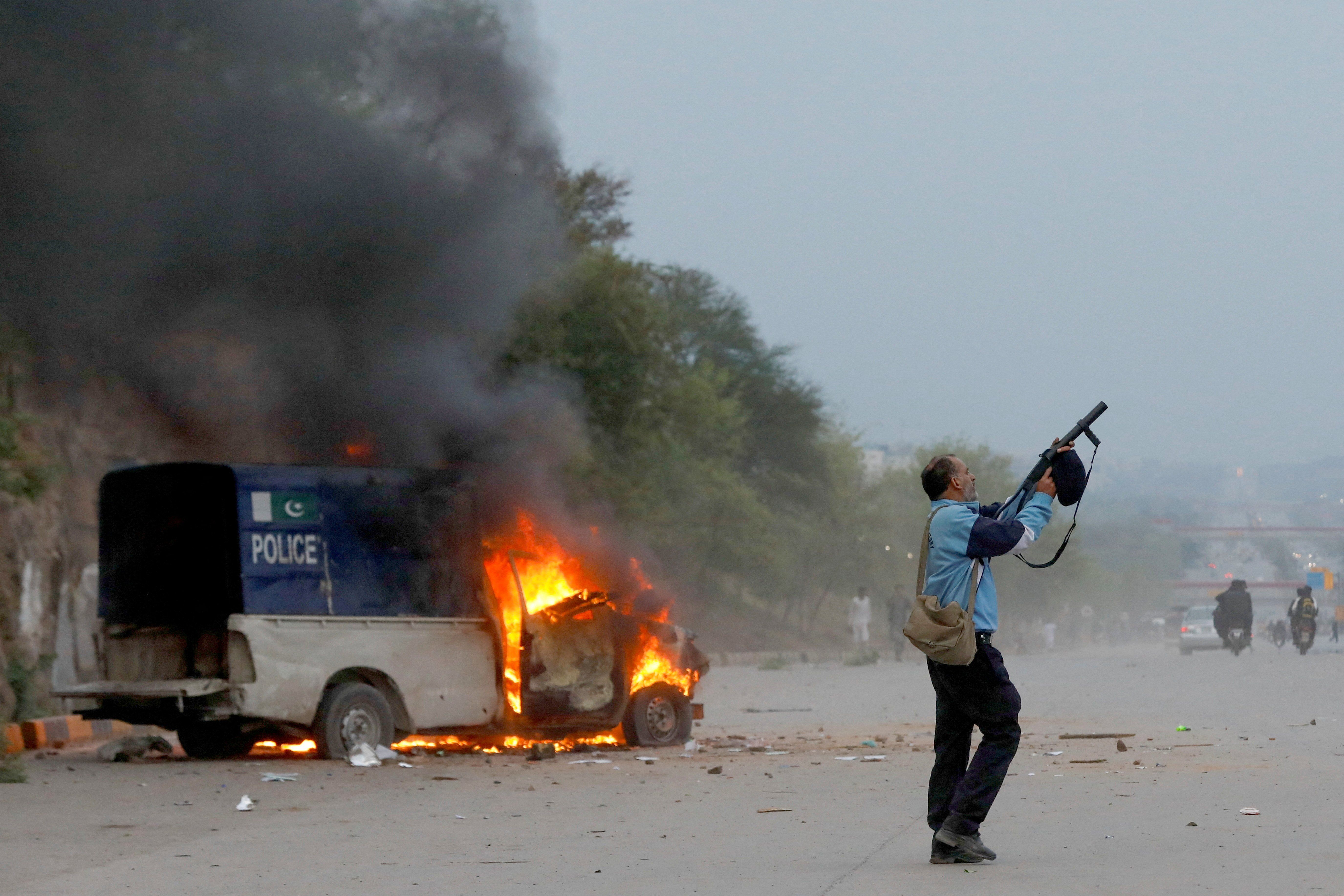 A police officer fires a tear gas can as supporters of former Pakistani Prime Minister Imran Khan clash with police outside a Federal Judicial Complex in Islamabad.