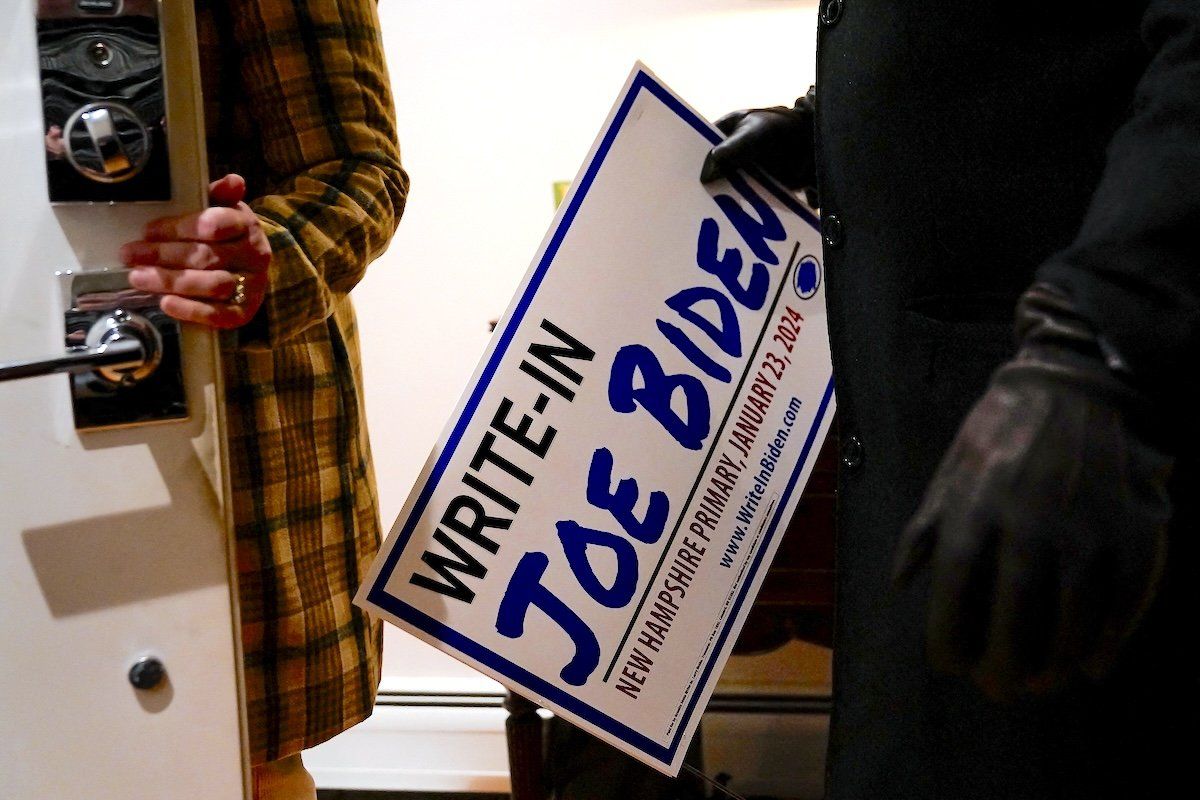 ​A potential voter takes home a sign after attending a house party supporting the write-in campaign to put US President Joe Biden's name on the New Hampshire Democratic primary ballot. 