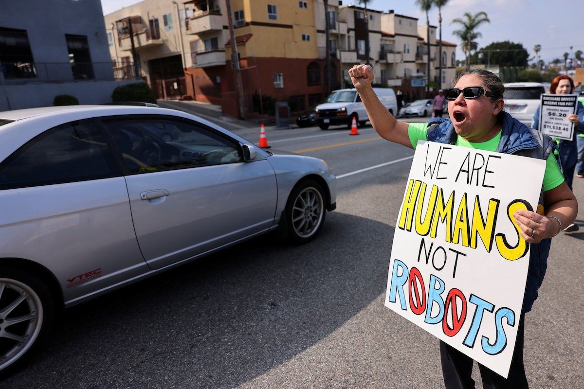 ​A rideshare driver in Los Angeles holds a placard, as Uber, Lyft, and DoorDash drivers strike in multiple US cities on Valentine's Day. 