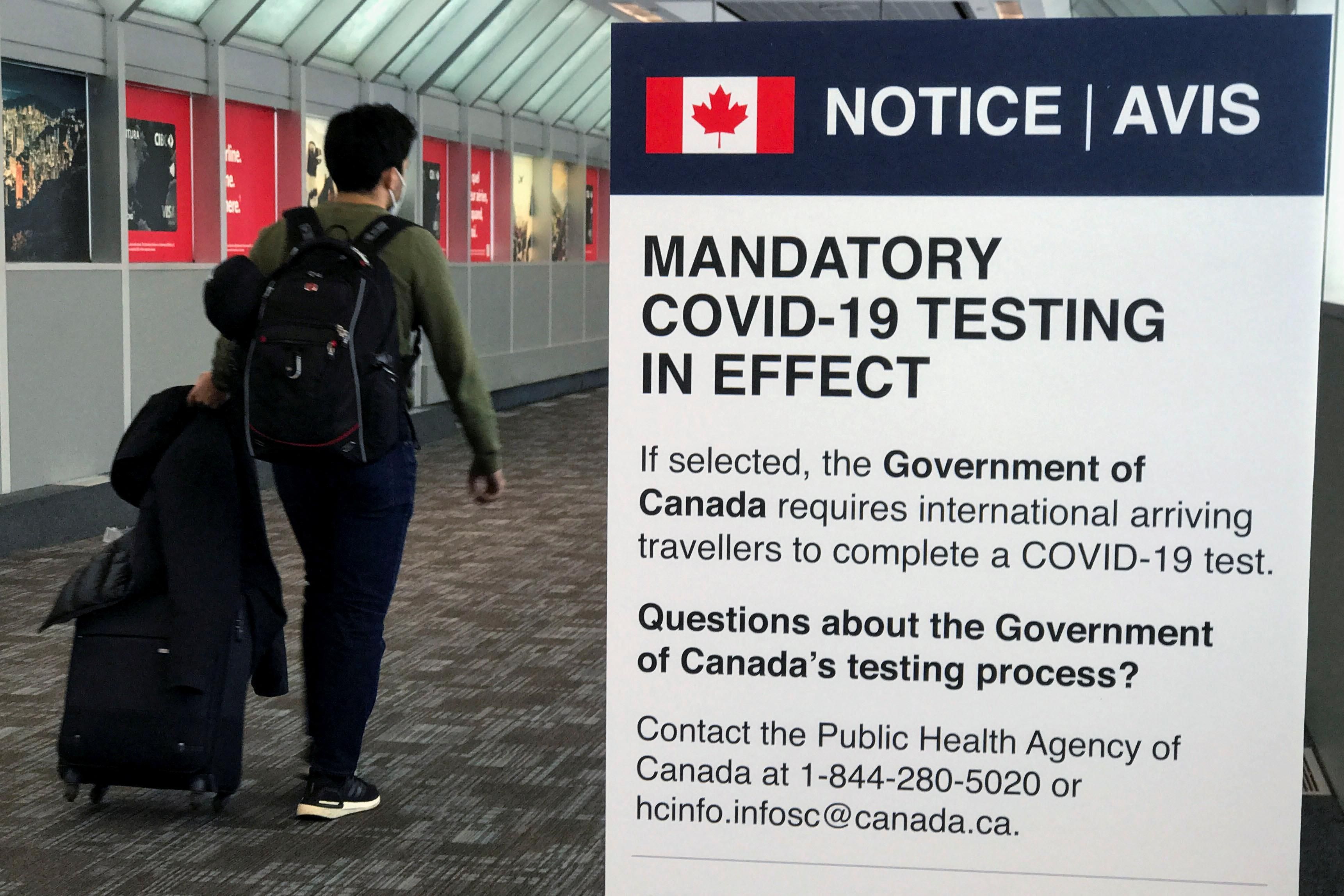 A traveler walks past a "Mandatory COVID Testing" sign at Pearson International Airport in Toronto.
