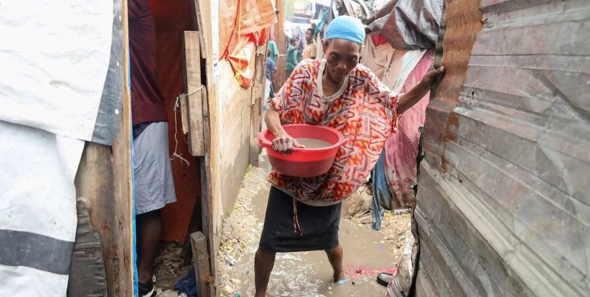 A woman carries water out of her home, after floods caused by the outer bands of Hurricane Melissa killed several people, in Port-au-Prince, Haiti, October 29, 2025.