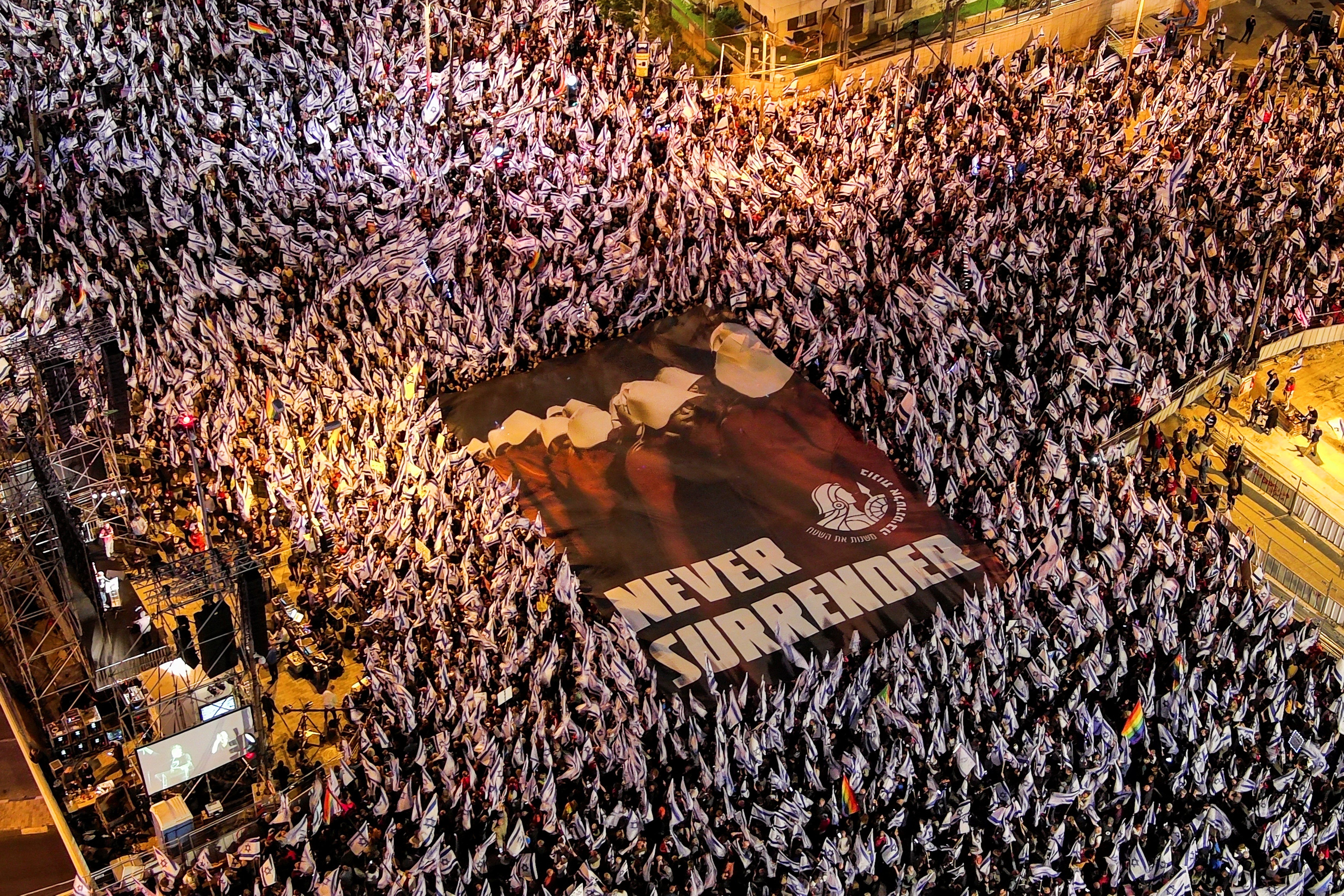 An aerial view shows protesters holding a sign depicting handmaidens from "The Handmaid's Tale" with the words "Never Surrender" as they demonstrate against Israeli PM Benjamin Netanyahu's judicial overhaul in Tel Aviv.