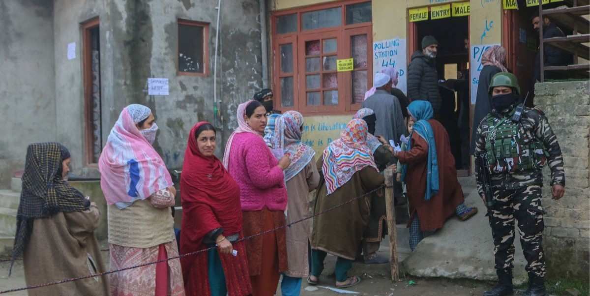 ​An Indian security personnel stands guard as women voters queue to cast their ballots at a polling station during the Budgam Assembly constituency bypoll in Budgam district, Jammu and Kashmir, on November 11, 2025. 