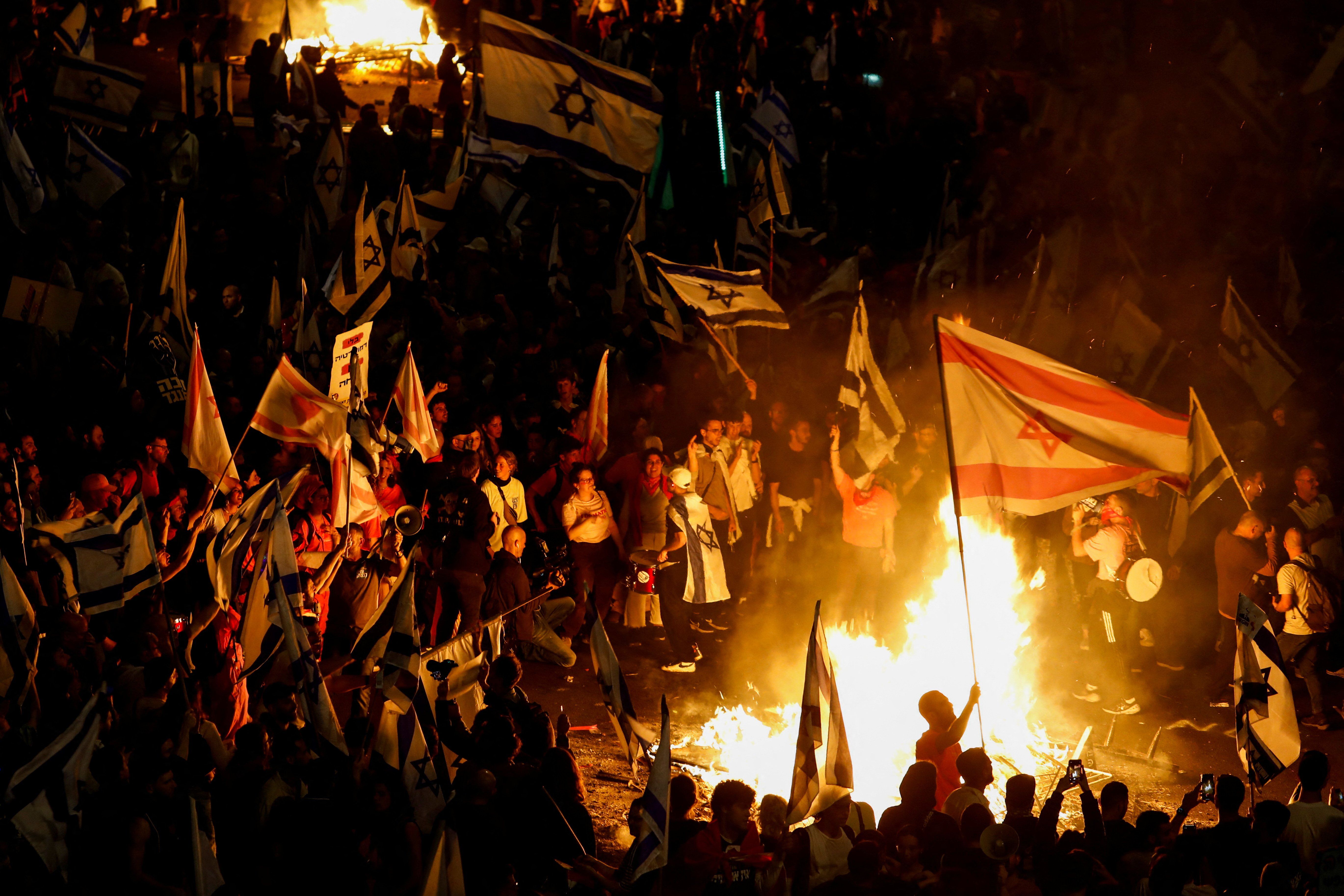 Fire burns as people attend a demonstration after Israeli PM Benjamin Netanyahu dismissed the defense minister, Tel Aviv, Israel, March 27, 2023.