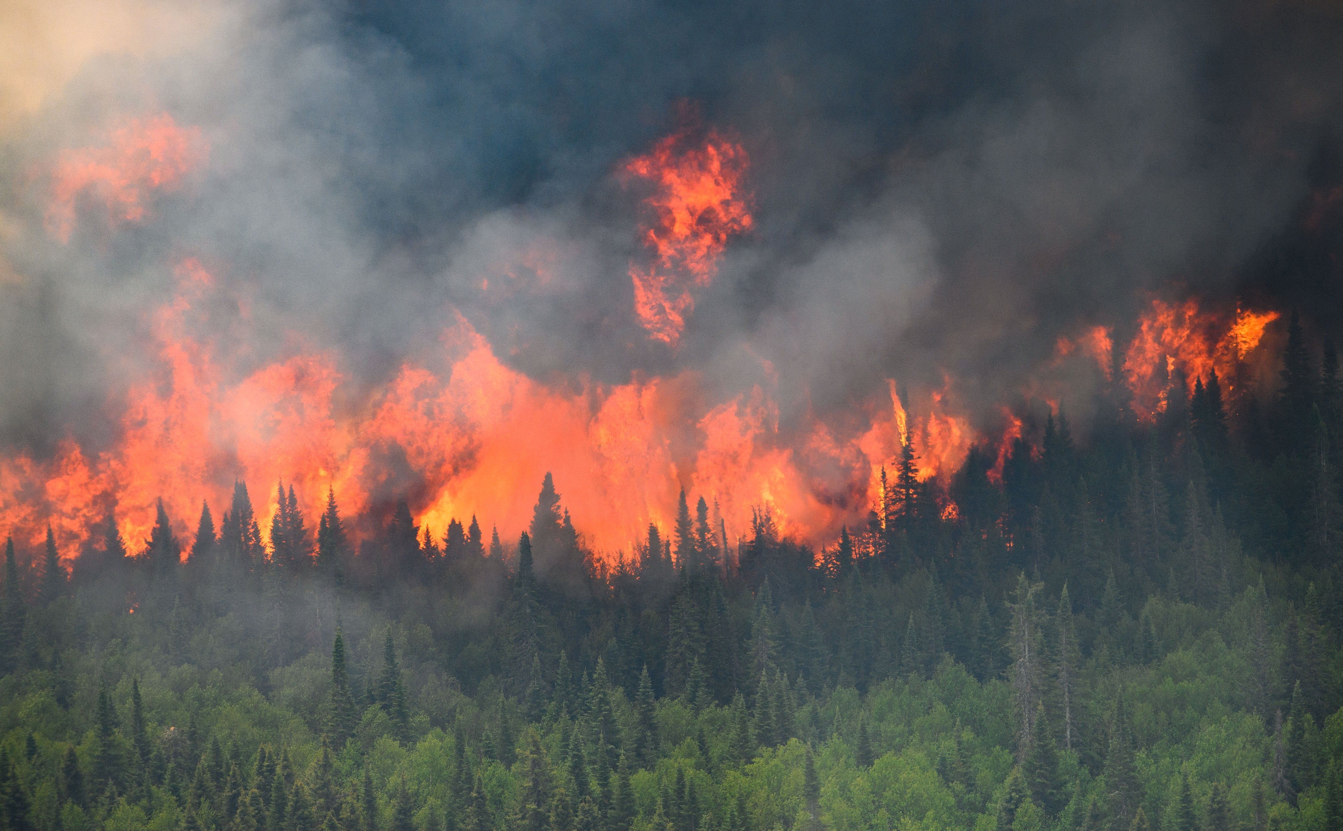 Flames reach upwards along the edge of a wildfire as seen from a Canadian military helicopter near Mistissini, Quebec.
