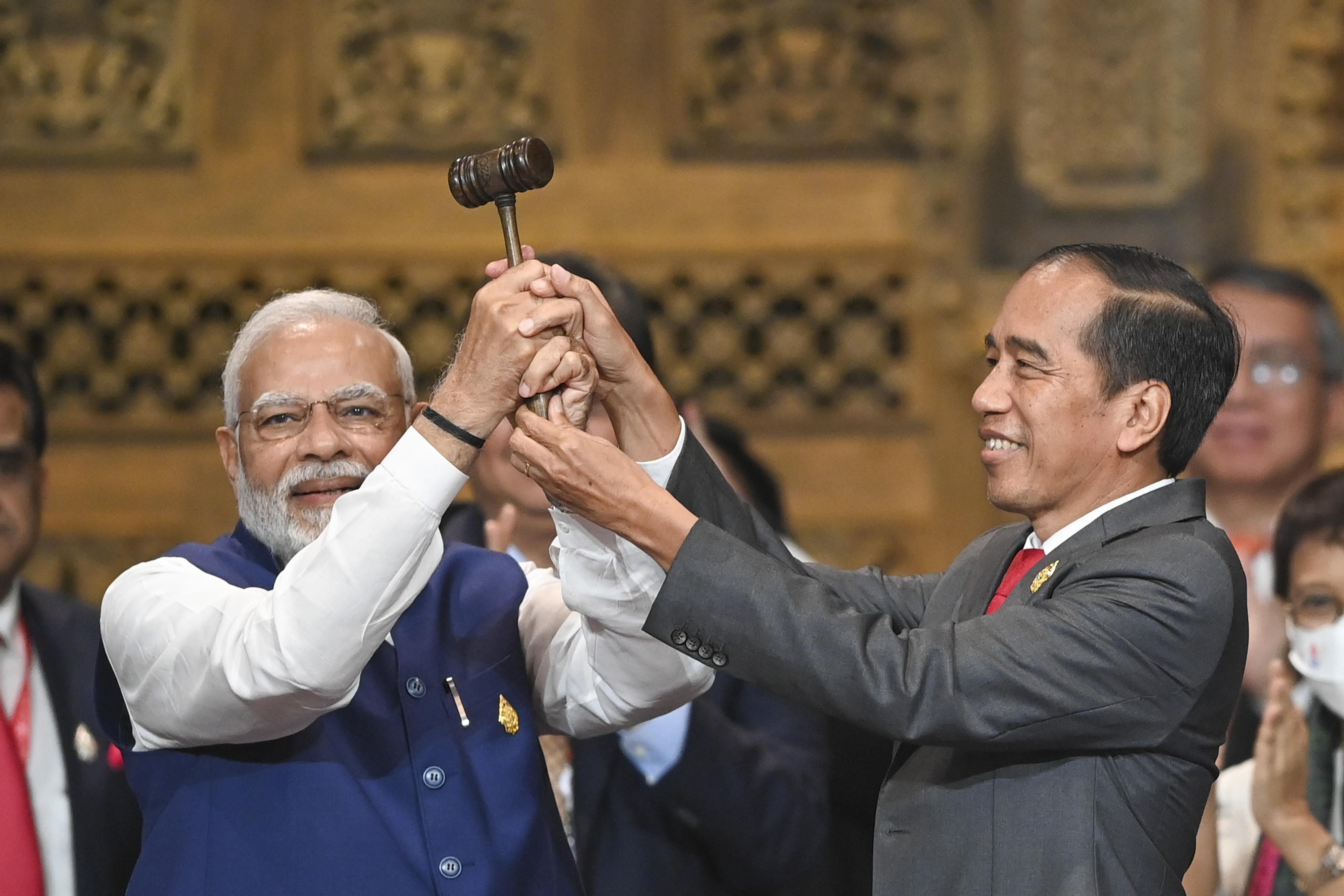 Indonesian President Joko Widodo (R) hands over the G-20 presidency gavel to India's PM Narendra Modi (L) at the G-20 summit in Bali.