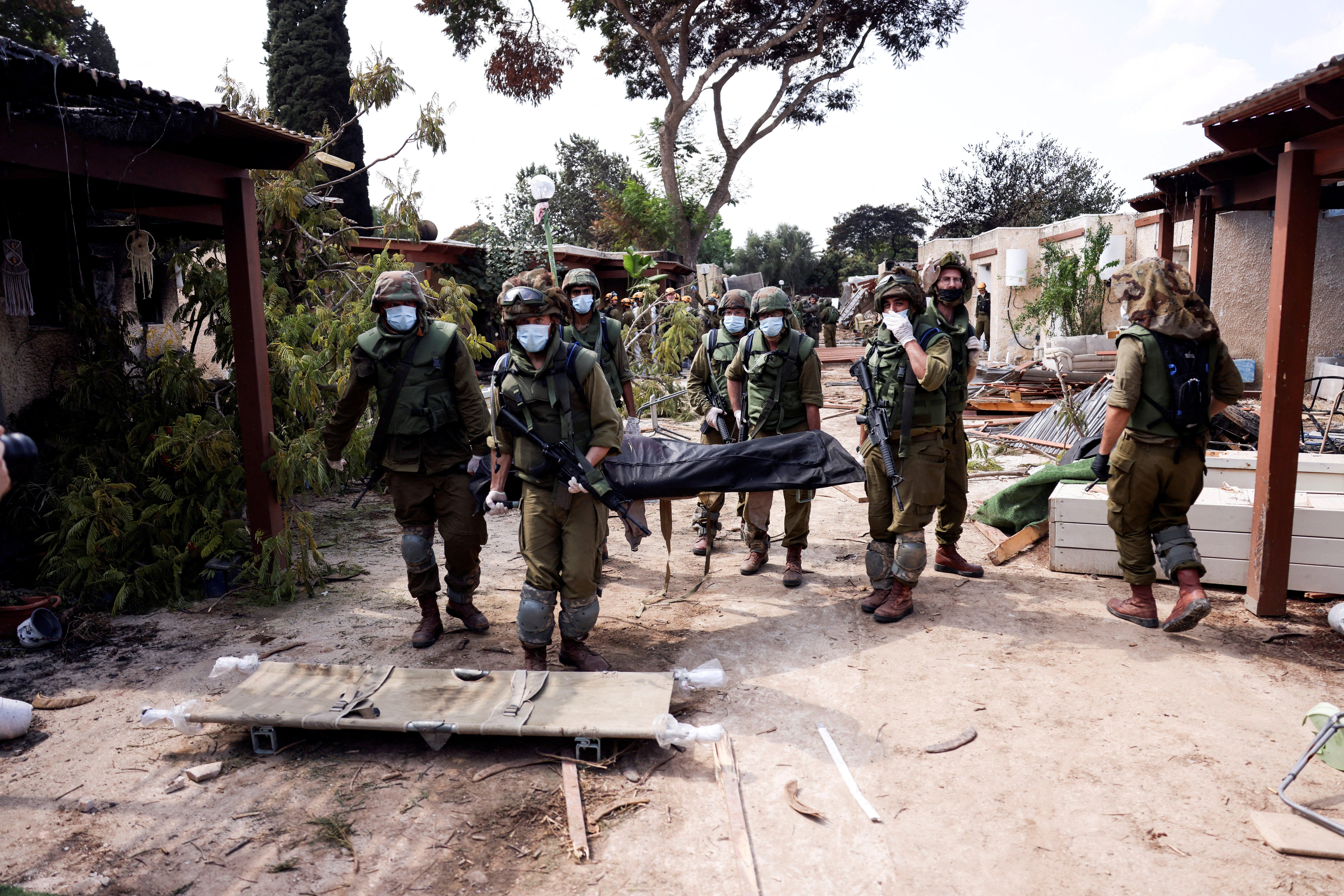 Israeli soldiers carry the body of a victim of an attack by militants from Gaza at Kibbutz Kfar Aza, in southern Israel. 