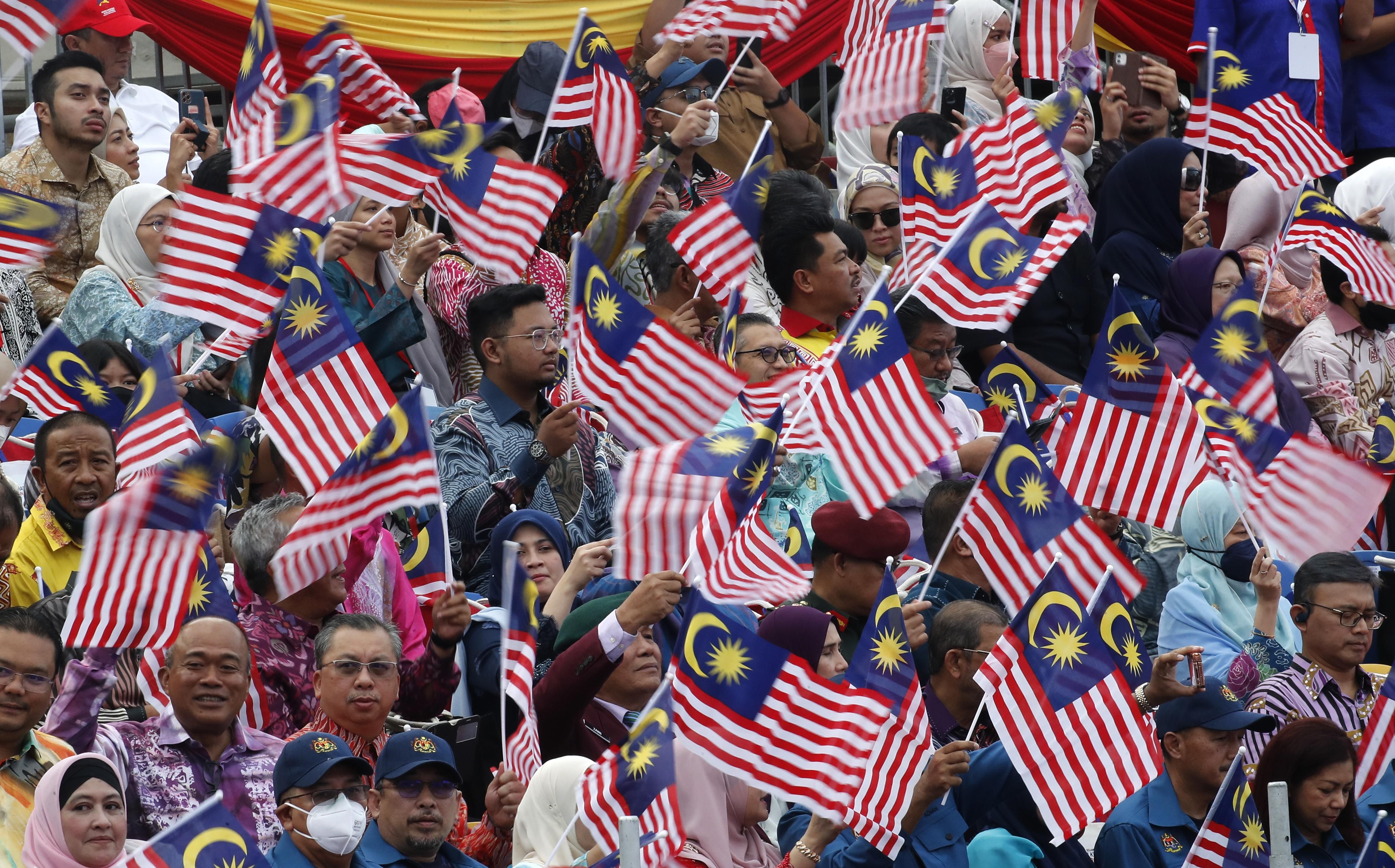 Malaysians wave flags during the 65th National Day celebrations parade in Kuala Lumpur.