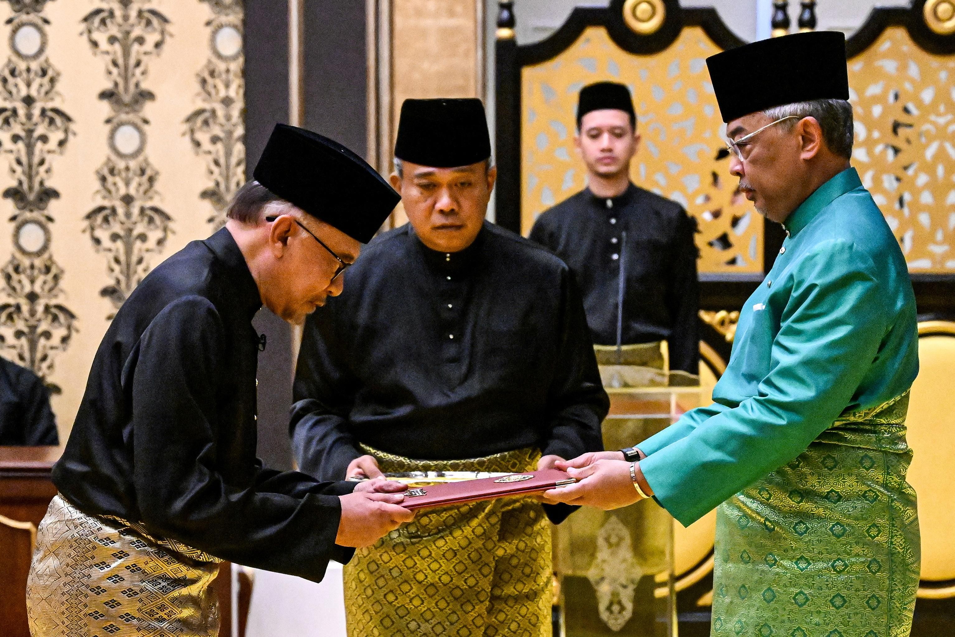 Malaysia's King Sultan Abdullah Sultan Ahmad Shah (R) and newly appointed Prime Minister Anwar Ibrahim (L) take part in the swearing-in ceremony in Kuala Lumpur.