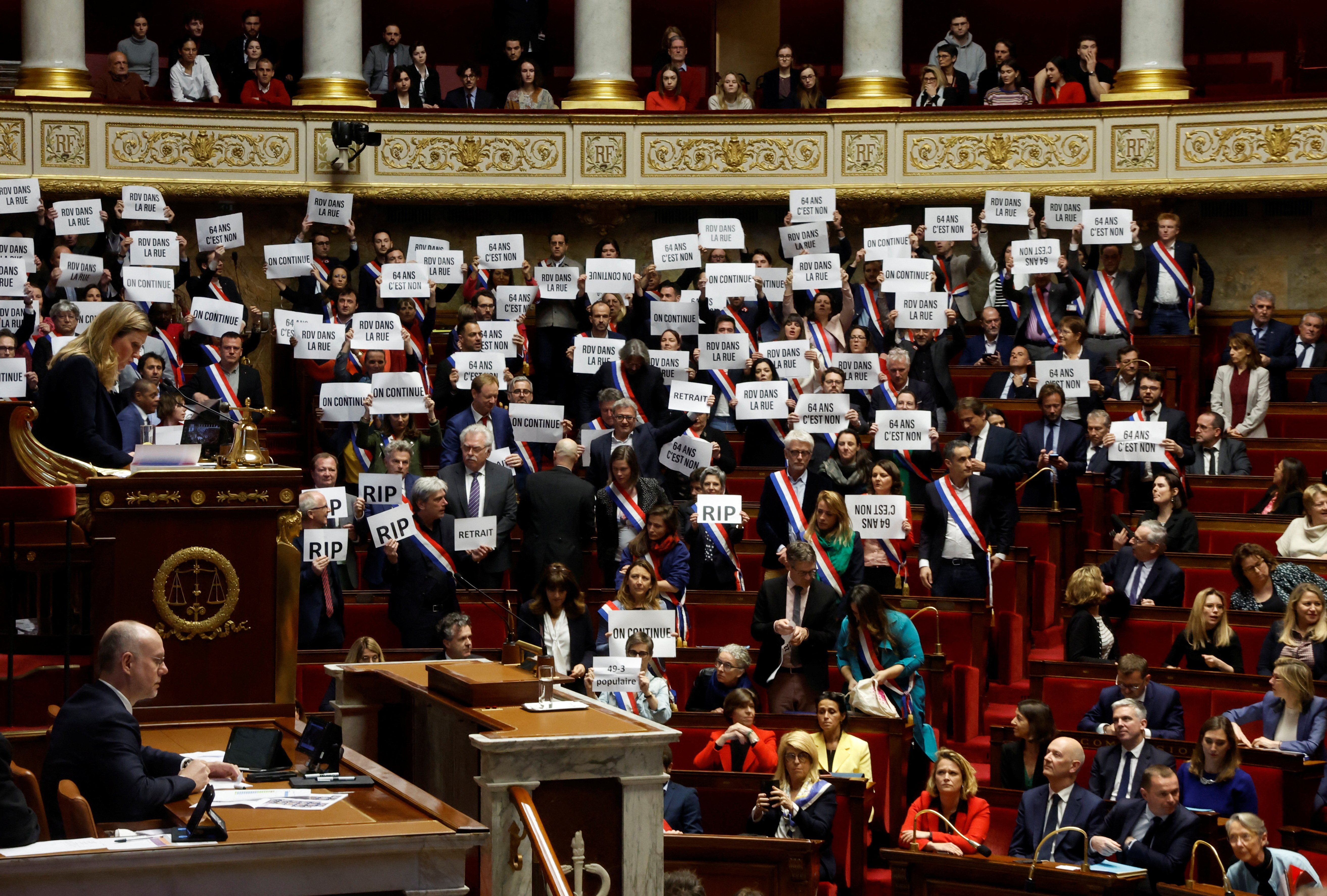 Members of parliament hold placards after the result of the vote on the first motion of no-confidence against the French government at the National Assembly in Paris, France, March 20, 2023.