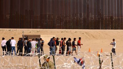Migrants gather near the border wall