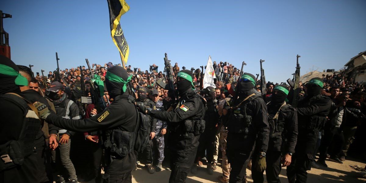​Palestinian Hamas and Islamic Jihad fighters form a human chain in front of the crowd gathered near the family home of slain Hamas leader Yahya Sinwar, where the Hamas militant group prepares to hand over Israeli and Thai hostages to a Red Cross team in Khan Yunis, on January 30, 2025, as part of their third hostage-prisoner exchange..