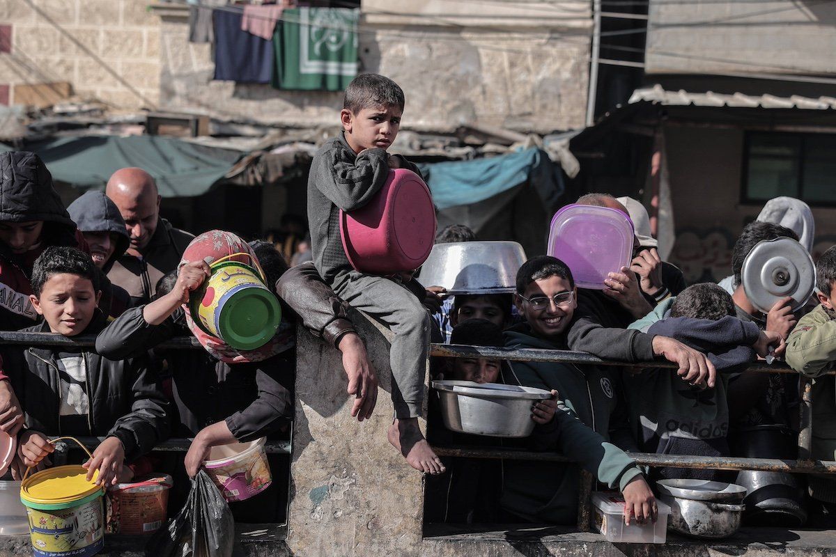 Palestinians wait to collect food at a donation point in a refugee camp in Rafah in the southern Gaza Strip on December 24, 2023.