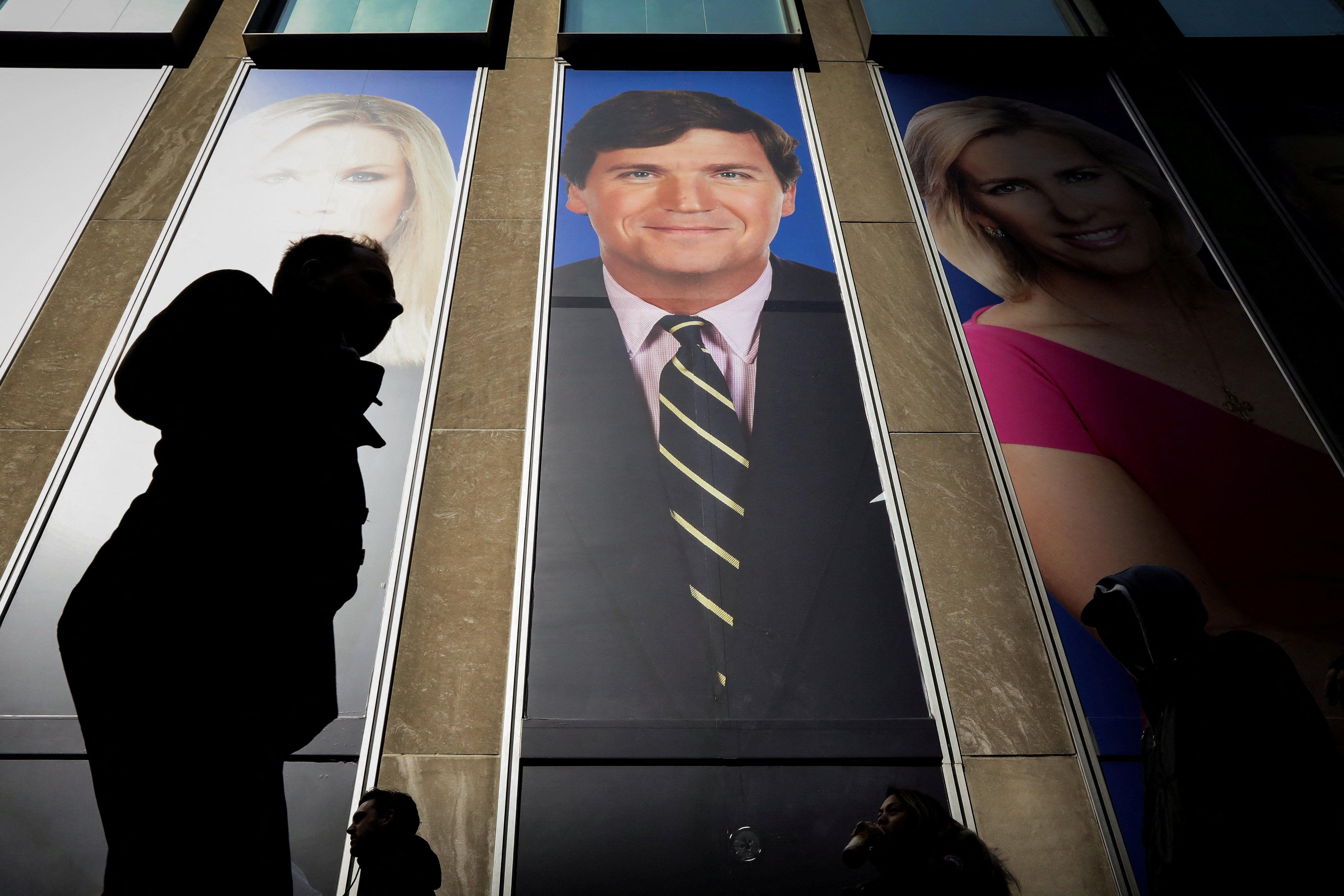 People pass by a promo of Tucker Carlson on the Fox Corp. building in New York.