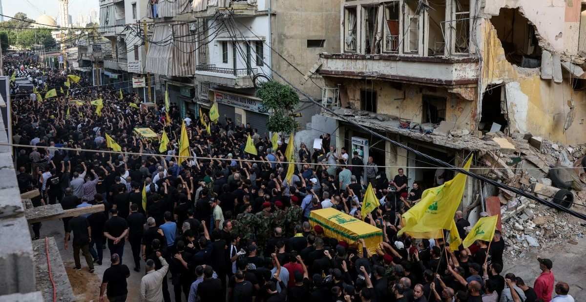 ​People walk past a damaged building during the funeral of Hezbollah's top military official, Haytham Ali Tabtabai, and of other people who were killed by an Israeli airstrike on Sunday, despite a U.S.-brokered truce a year ago, in Beirut's southern suburbs, Lebanon November 24, 2025. 