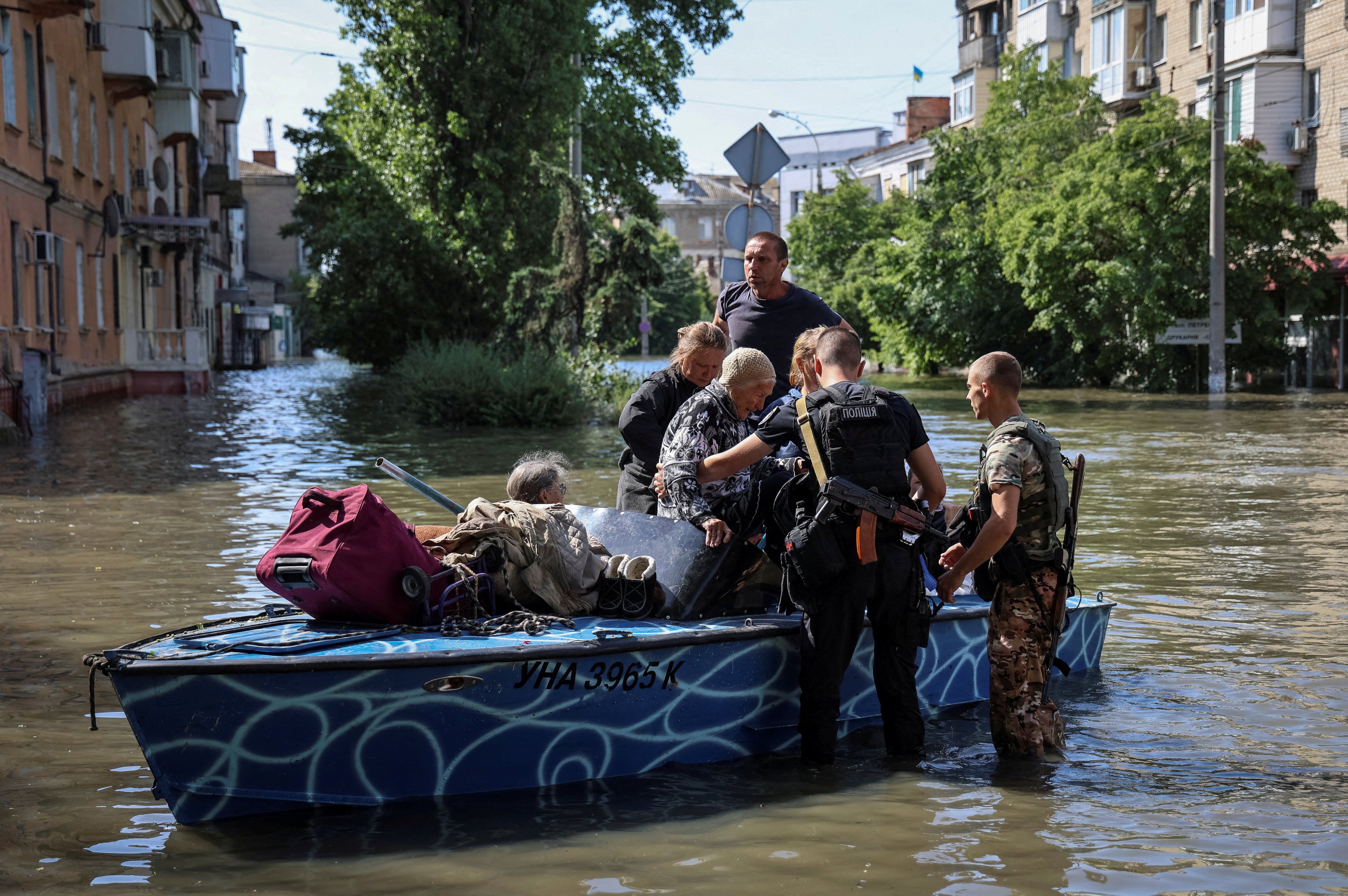 Police evacuate local residents from a flooded area after the Nova Kakhovka dam breached in Kherson, Ukraine.