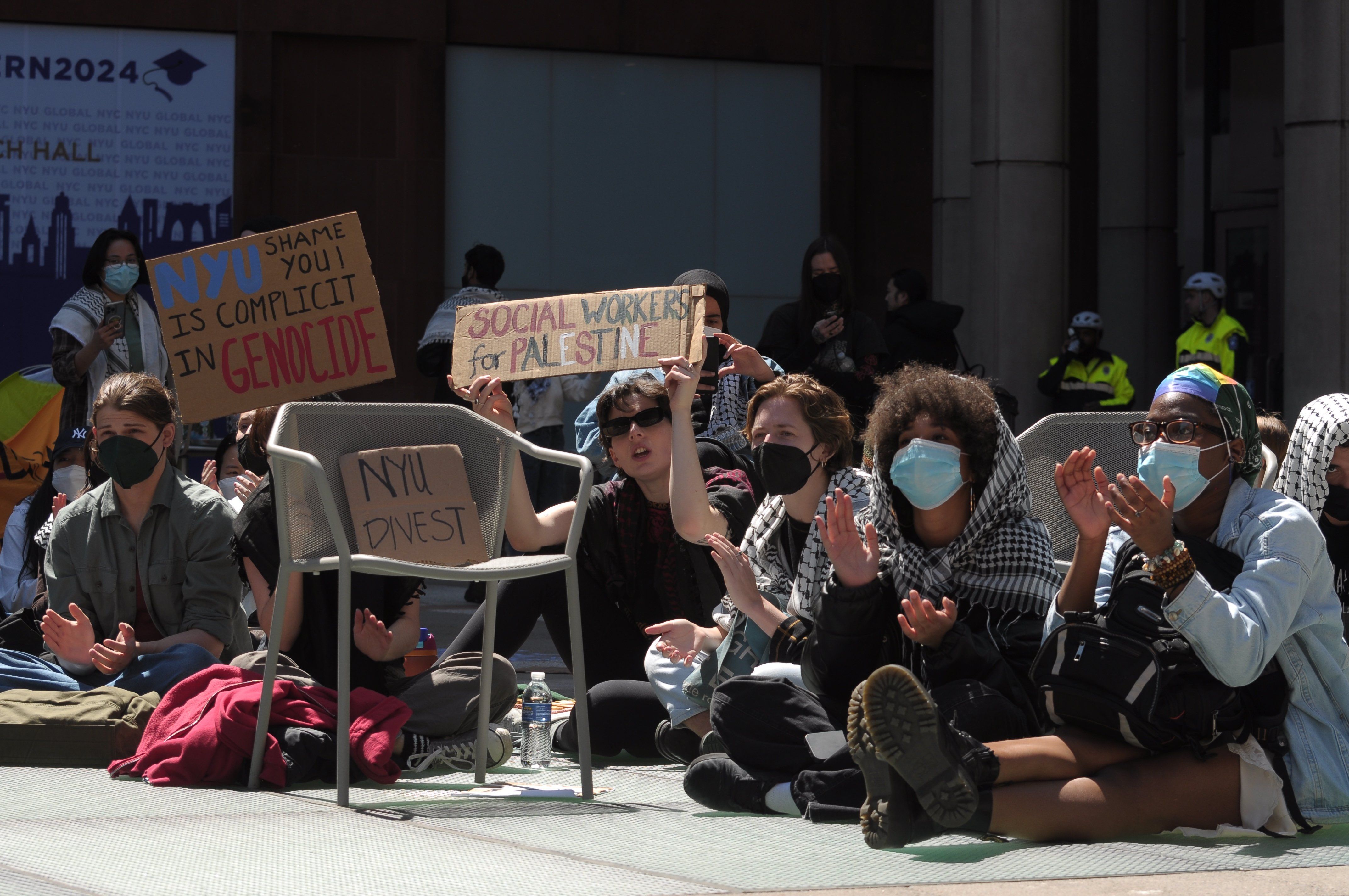 Pro-Palestine protesters hold placards expressing their opinion as they participate in a sit-in demonstration at New York University.