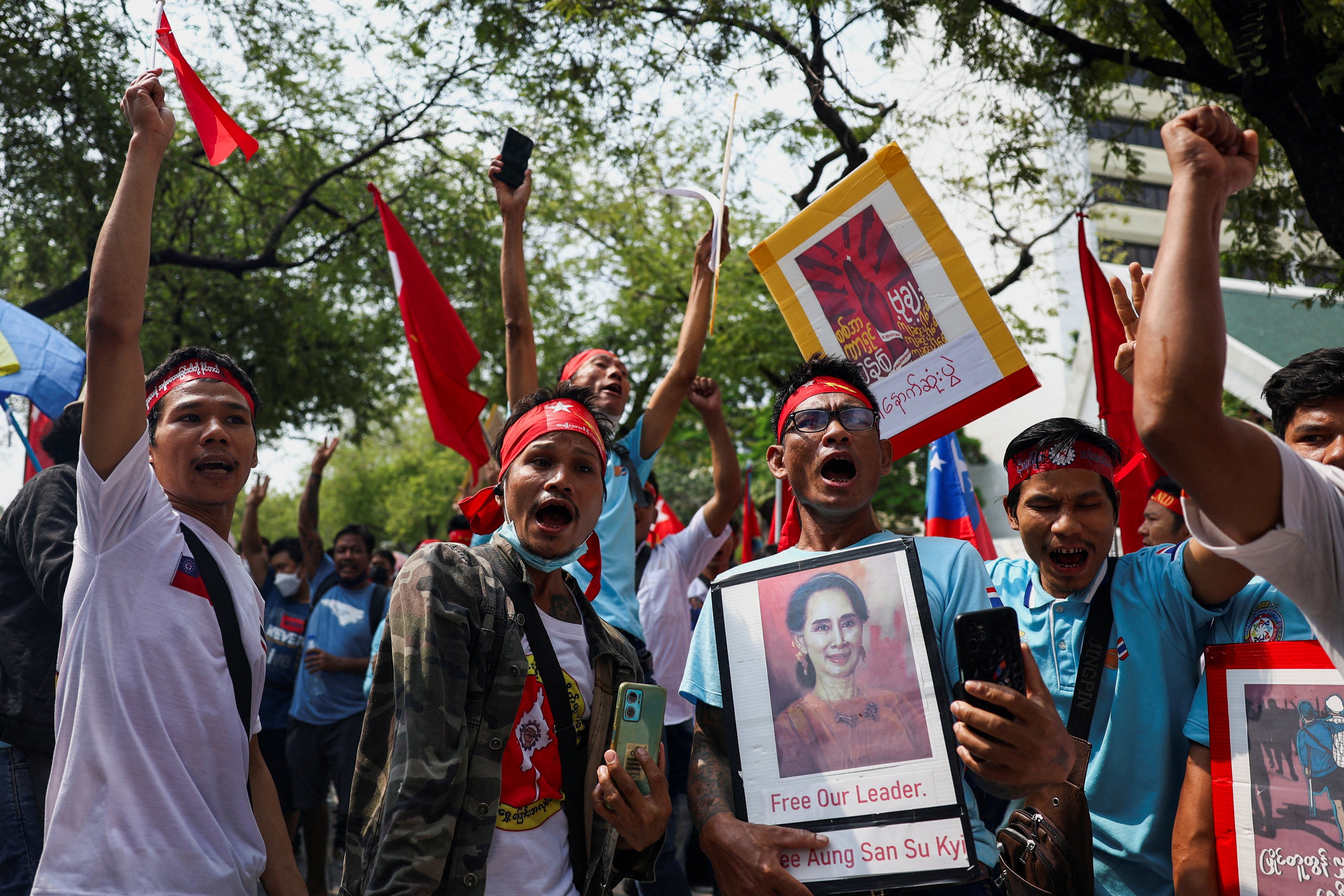 Protesters hold up a portrait of Aung San Suu Kyi and raise three-finger salutes
