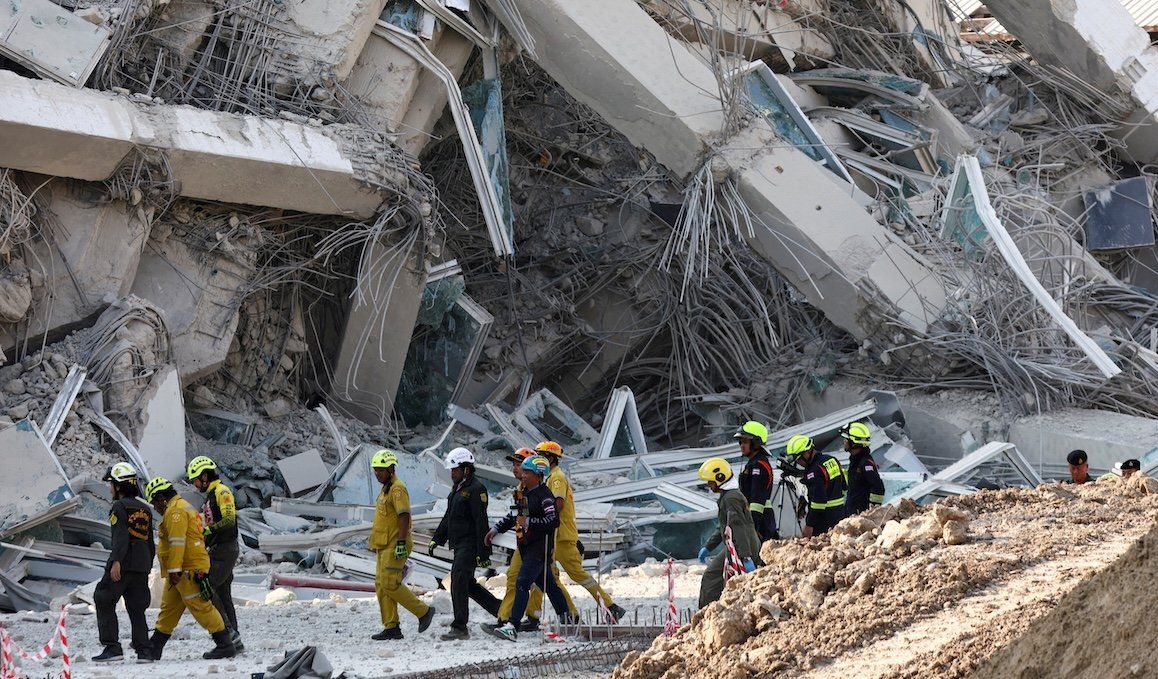 ​Rescue personnel walk near a building that collapsed after a strong earthquake struck central Myanmar on Friday, March 28, 2025.