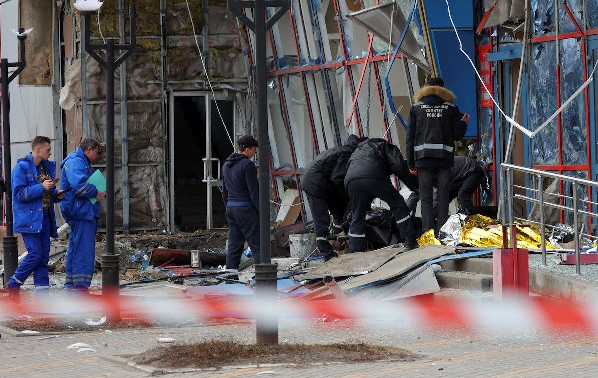 ​Specialists tend to the body of a victim outside a damaged shopping center hit by a missile strike in Belgorod, Russia, on Feb. 15, 2024. 