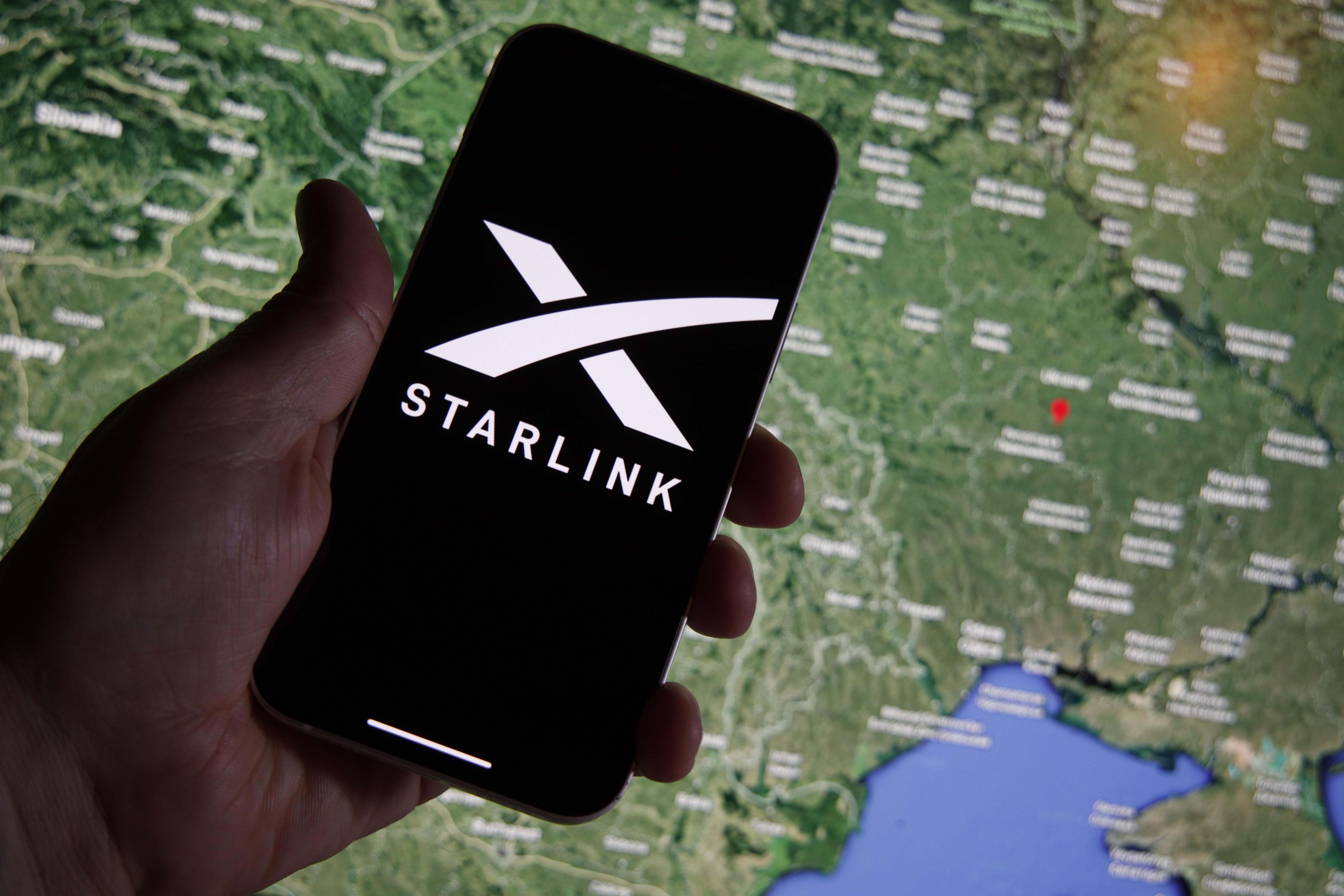 Starlink logo seen on a mobile device with Ukraine on a map in the background.