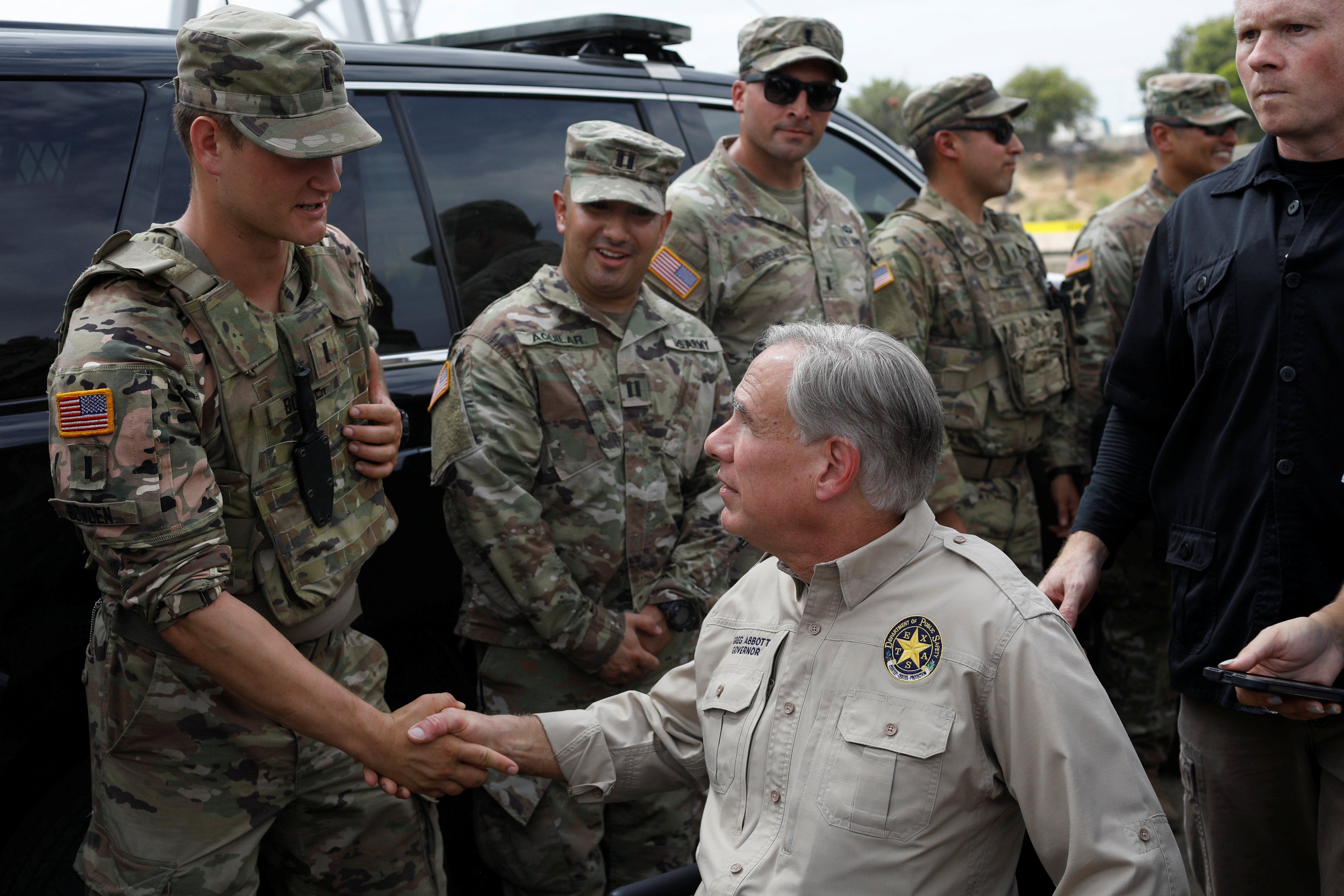 ​Texas Governor Gregg Abbott shakes hands with a U.S. Soldier after a news conference near the International Bridge between Mexico and the U.S., where migrants seeking asylum in the U.S. are waiting to be processed, in Del Rio, Texas, U.S., September 21, 2021. 