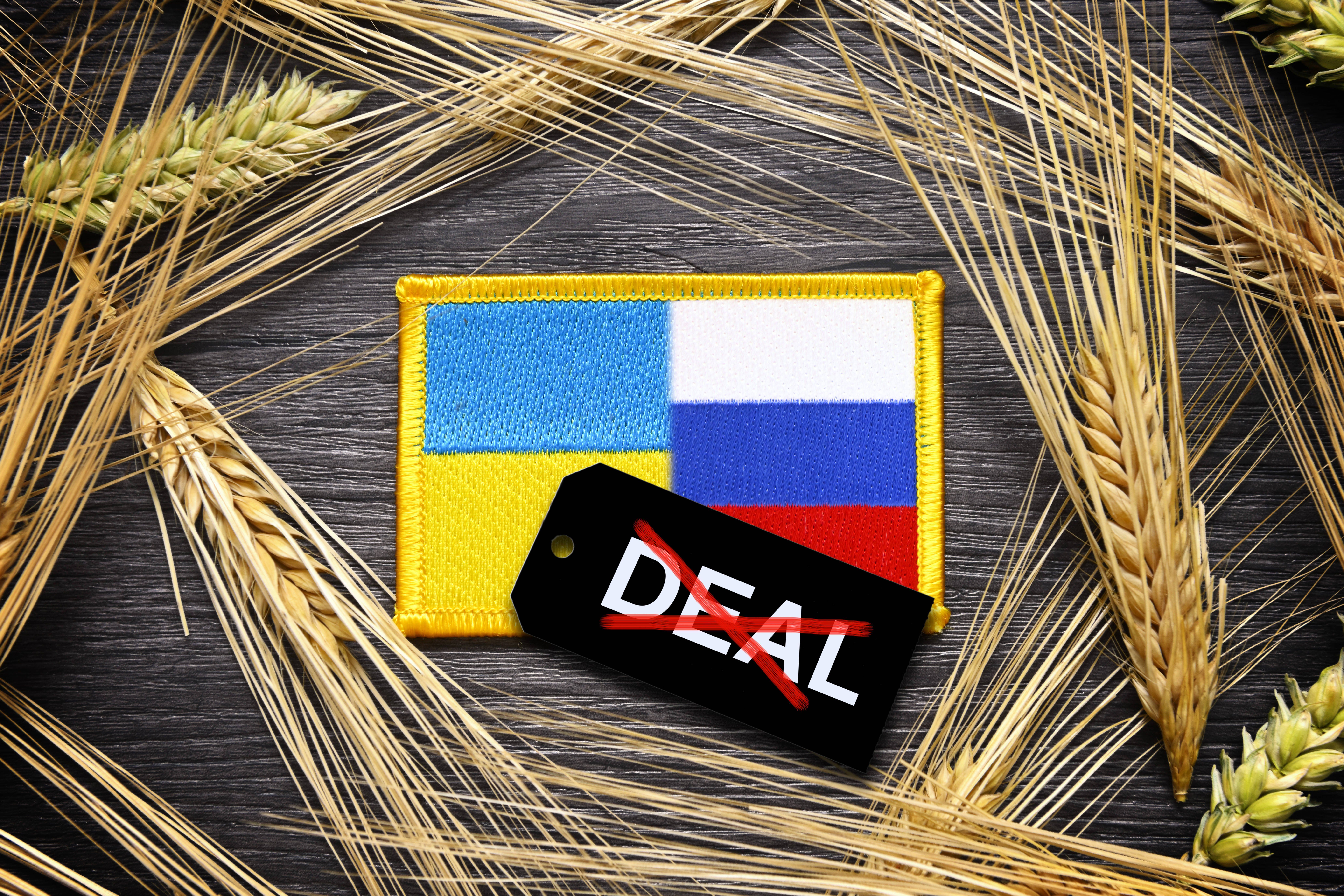 The flags of Ukraine and Russia surrounded by ears of grain and label with crossed-out inscription "Deal."