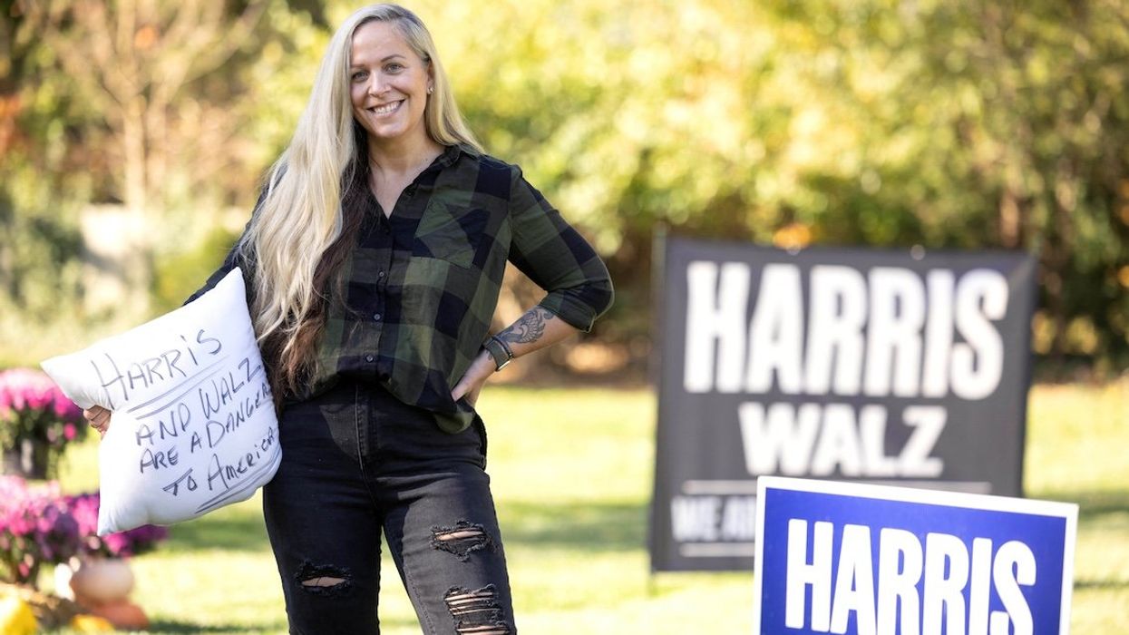 Lissa Smith poses with lawn signs in support of Kamala Harris, and a pillow someone threw in her yard after several signs, previously displayed on her lawn, were taken outside her home in Indianapolis, Indiana, on Oct. 27, 2024.