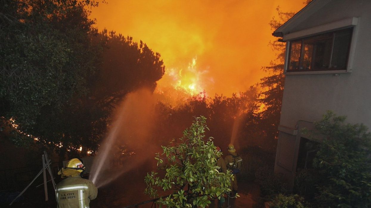 Los Angeles City firemen spray water to protect houses threatened by a brush fire in Griffith Park, Los Angeles May 8, 2007. The fire broke out in the hills above Los Angeles forcing evacuation of the city's largest park and zoo. Local media reported that authorities have arrested an arson suspect who was badly burned.