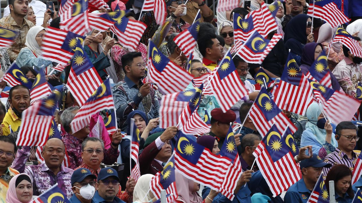 Malaysians wave flags during the 65th National Day celebrations parade in Kuala Lumpur.