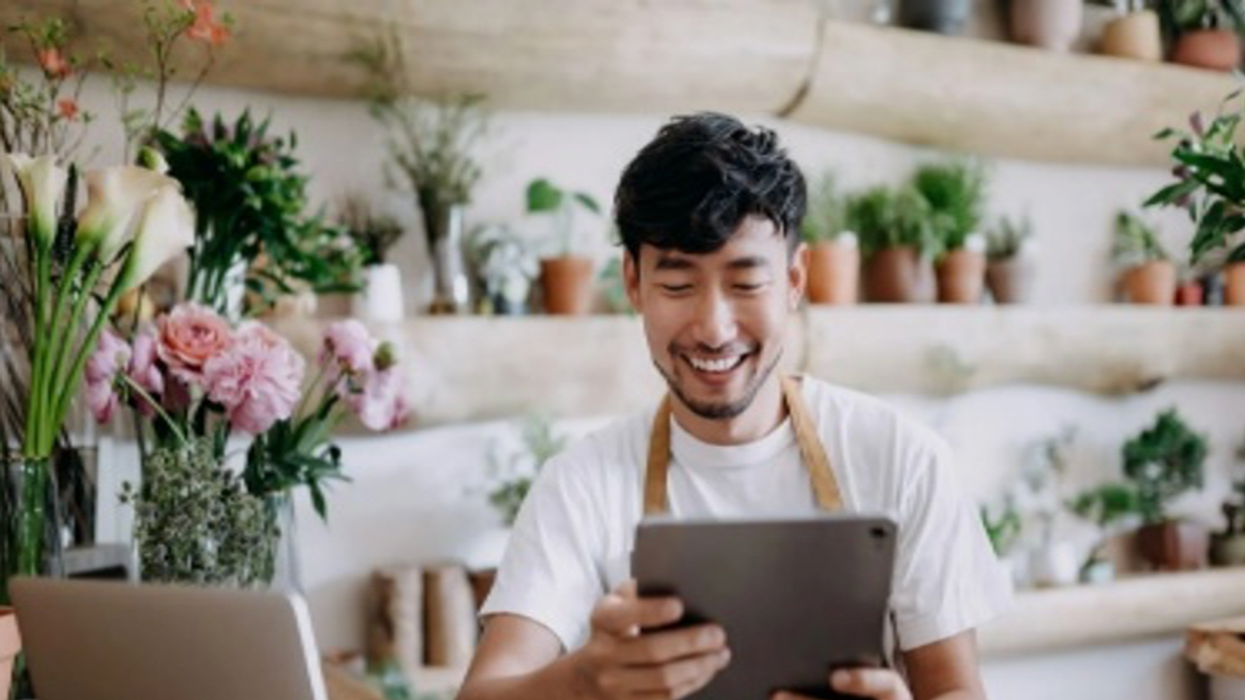 Man smiling using a tablet in a plant shop.
