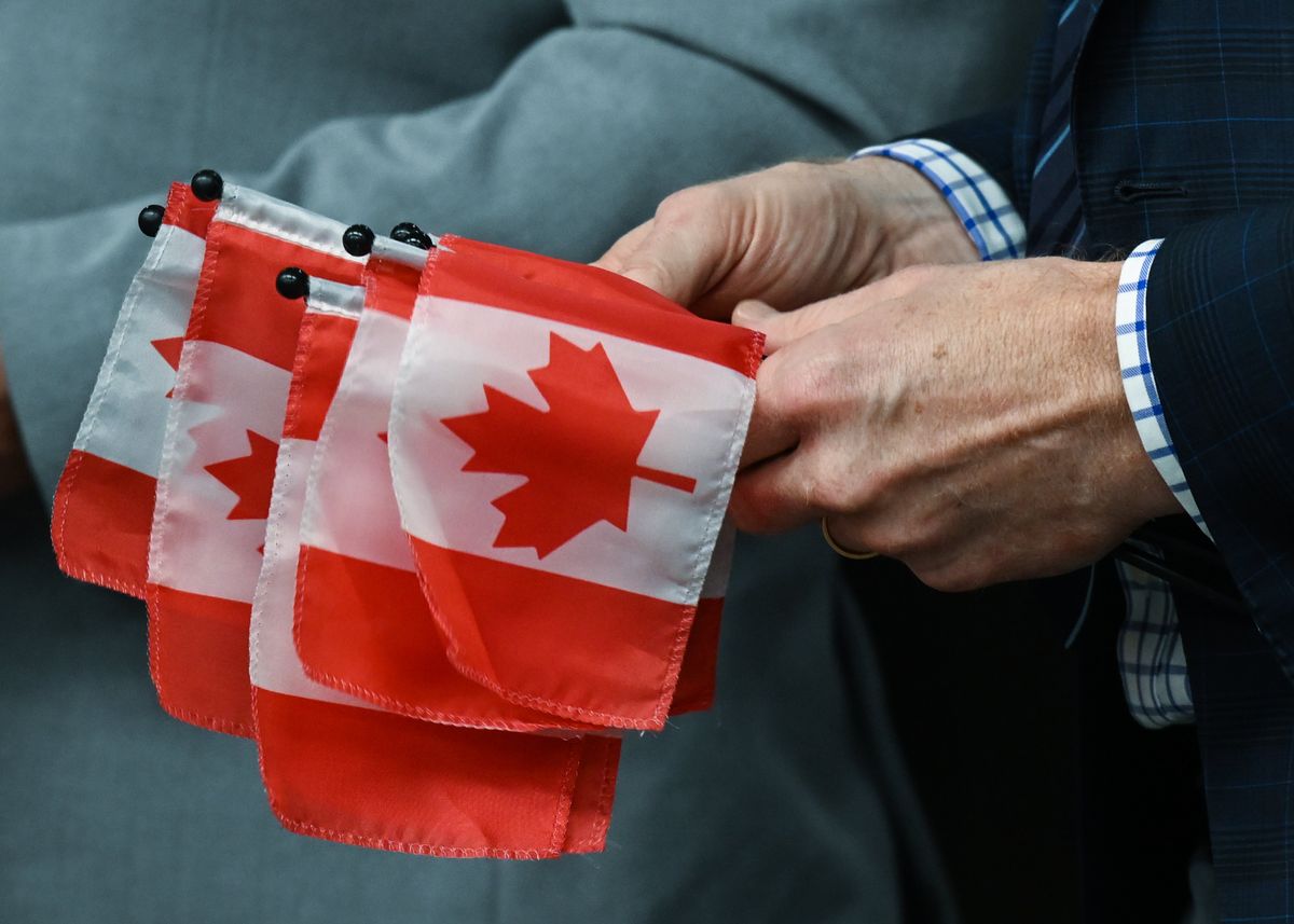 Marc Miller, Minister of Immigration, Refugees and Citizenship, hands small Canadian flags to 53 new Canadian citizens representing 22 diverse nations, as they embark on their citizenship journey during a special ceremony at Canada Place, on Oct. 12, 2023, in Edmonton, Alberta. 