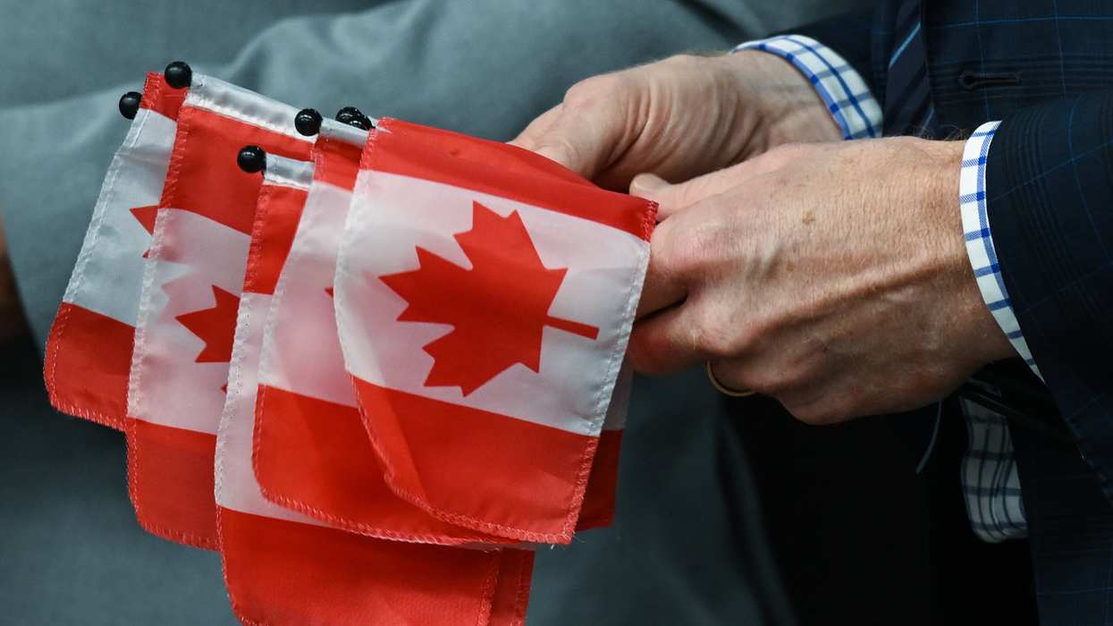Marc Miller, Minister of Immigration, Refugees and Citizenship, hands small Canadian flags to 53 new Canadian citizens representing 22 diverse nations, as they embark on their citizenship journey during a special ceremony at Canada Place, on Oct. 12, 2023, in Edmonton, Alberta.