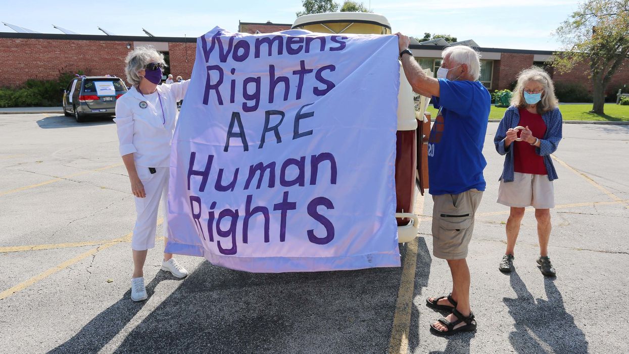 Mary Koczan, left, and Dennis Arnott, with his wife Jane, work on decorating, Saturday, August 22, 2020, in Sheboygan, Wis., Arnott's 1967 VW bus before a parade celebrating the 100th anniversary of the passing of the 19th Amendment, which gave women the right to vote
