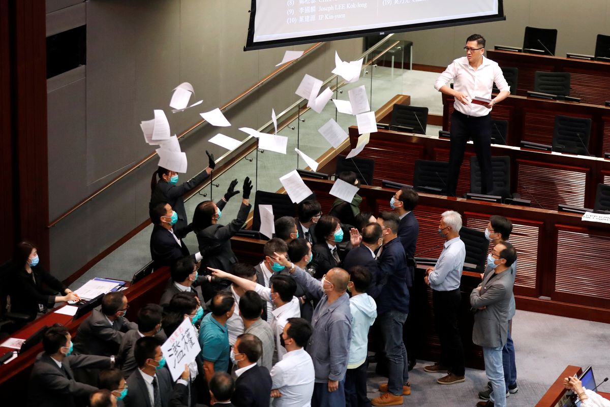 Mask-clad representatives in Hong Kong's legislature argue and throw papers in the air.