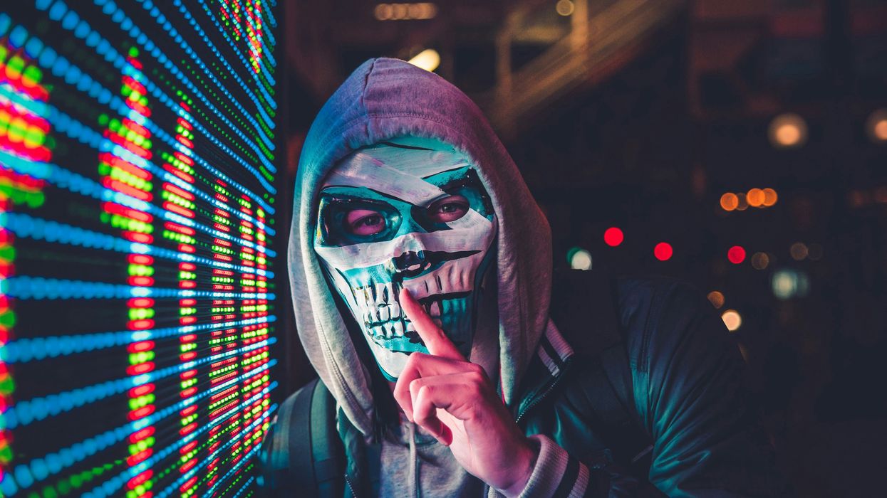 Masked person standing near LED sign.