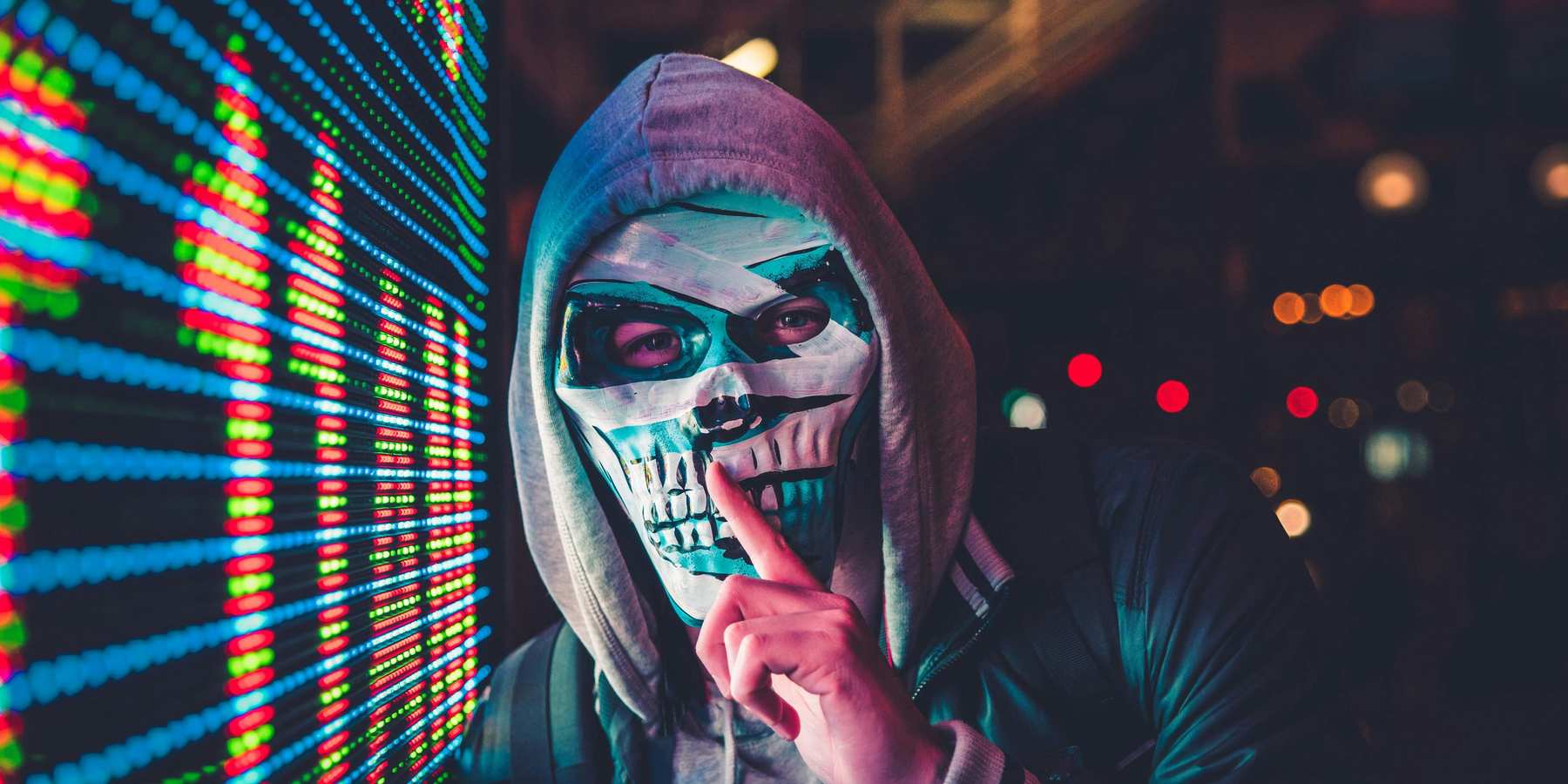 Masked person standing near LED sign.