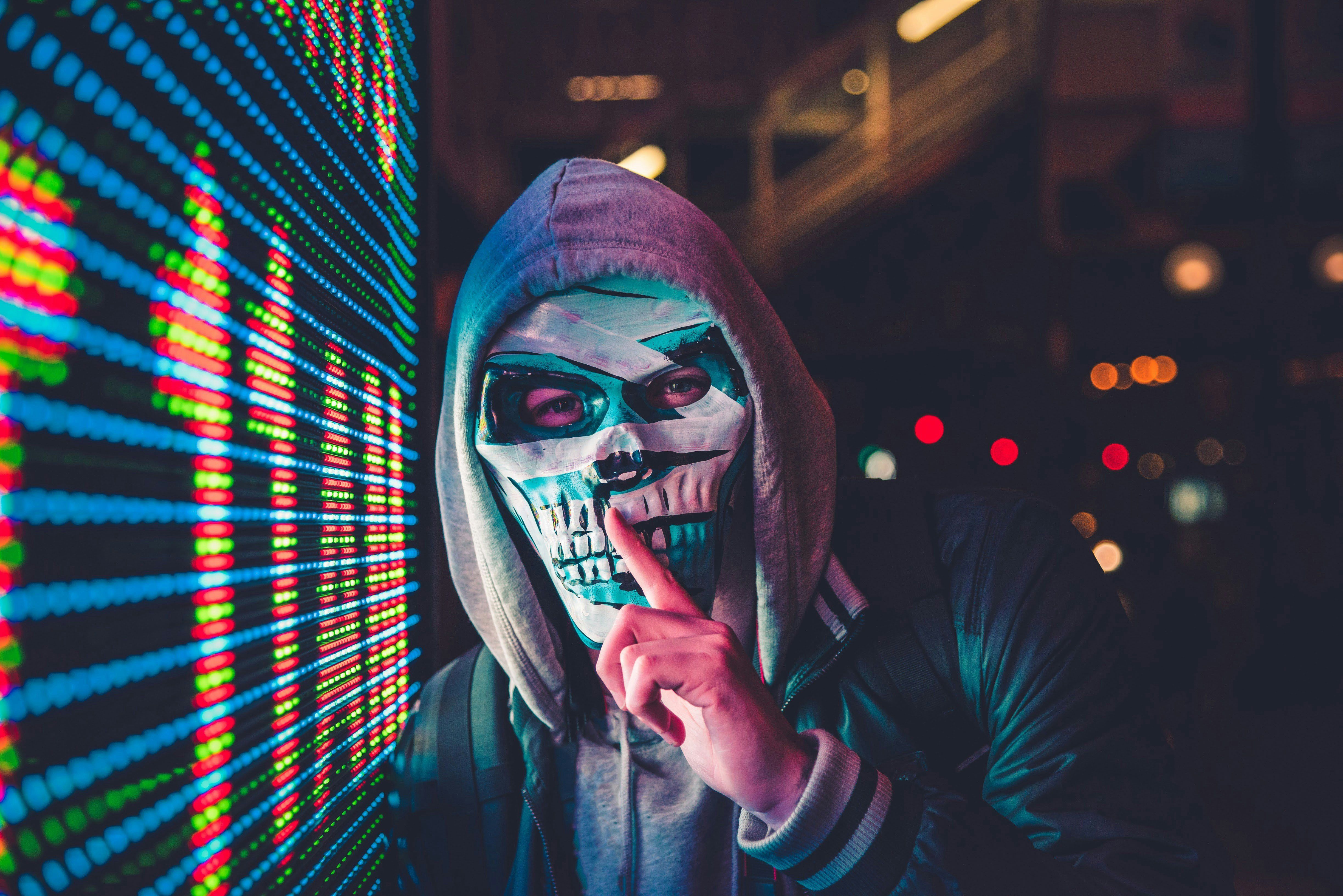 Masked person standing near LED sign.