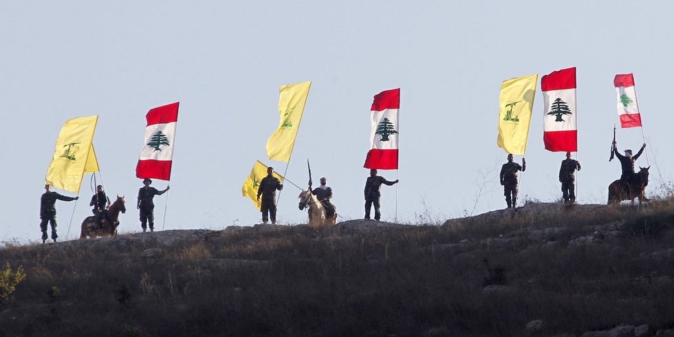 ​Members of Lebanon's Hezbollah wave Hezbollah and Lebanese flags during a rally in southern Lebanon marking the ninth anniversary of the end of the 2006 war with Israel, August 14, 2015.