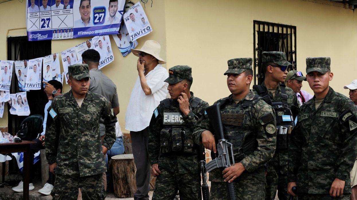 Members of security forces stand guard outside a polliong station, a week late in a special election, after the local governing party kept voting closed on election day, amid accusations of sabotage and fraud, in a presidential race still too close to call as counting continues, in San Antonio de Flores, Honduras, December 7, 2025.