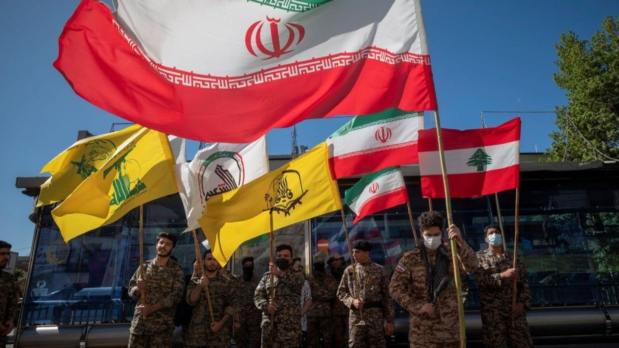 Members of the Basij paramilitary force hold Iranian flag, Lebanese flag, and various militia flags, during a rally commemorating International Quds Day in downtown Tehran, April 14, 2023.