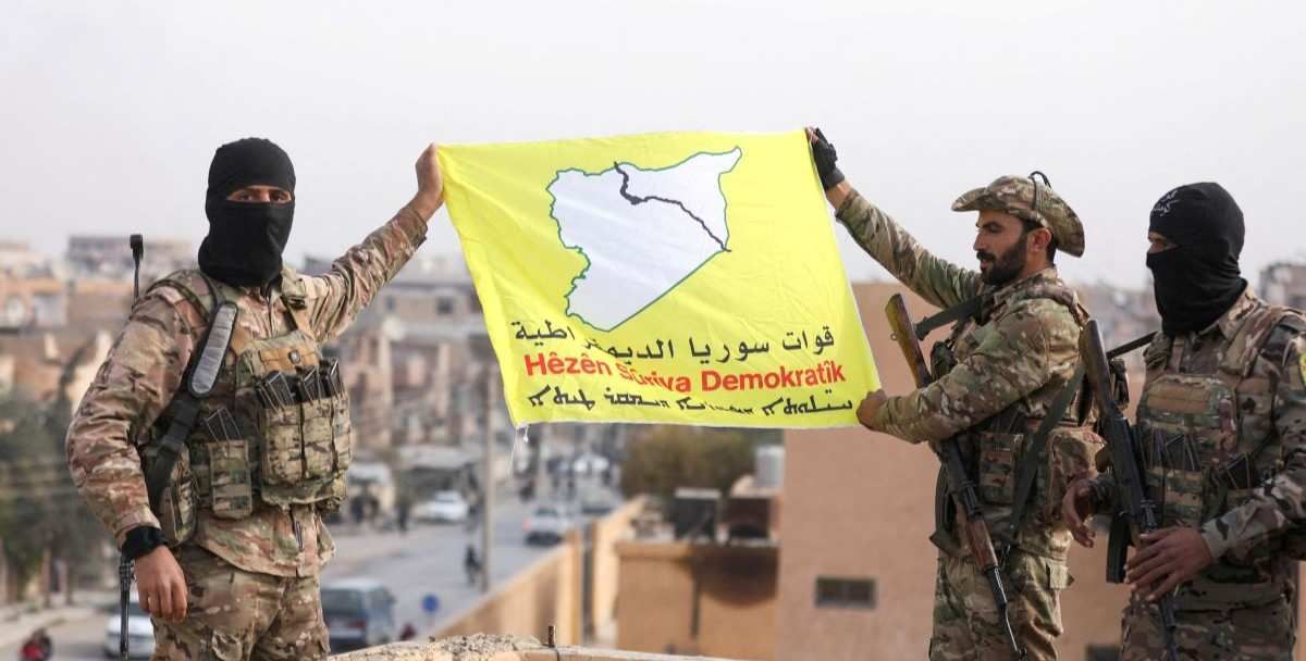 ​Members of the Kurdish-led Syrian Democratic Forces (SDF) hold a flag in the divided city of Deir al-Zor, Syria December 7, 2024. 