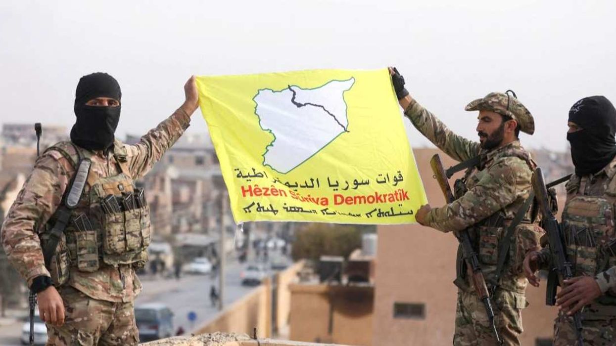 Members of the Kurdish-led Syrian Democratic Forces (SDF) hold a flag in the divided city of Deir al-Zor, Syria December 7, 2024.