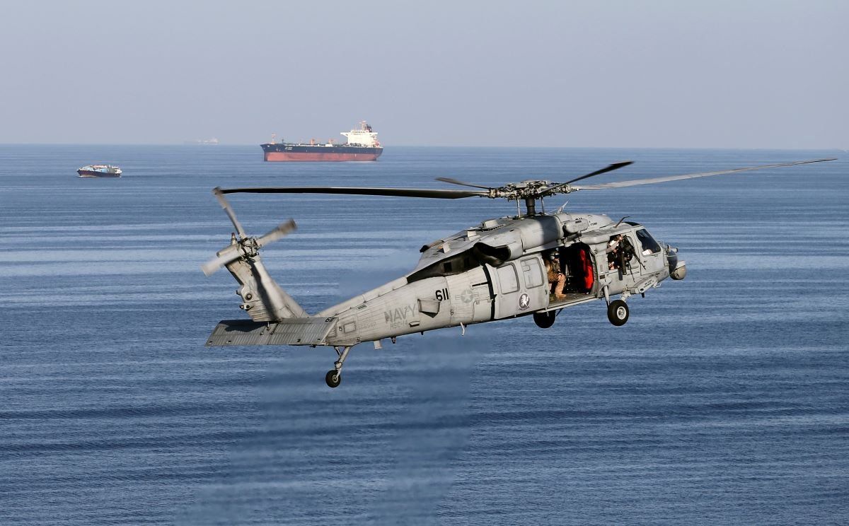 ​MH-60S helicopter hovers in the air with an oil tanker in the background as the USS John C. Stennis makes its way to the Gulf through the Strait of Hormuz, December 21, 2018. 