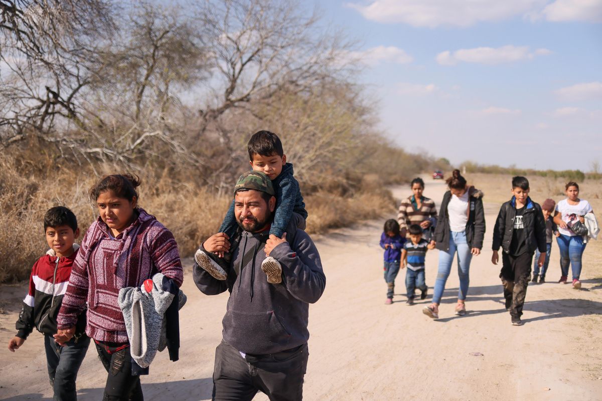 Migrant families with children walk along a dirt road after crossing the Rio Grande River into the United States from Mexico in Penitas, Texas, U.S., March 6, 2021.