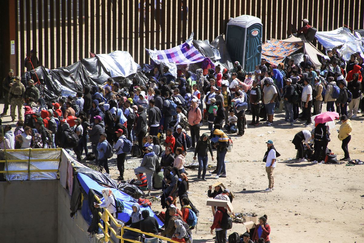 Migrants gather between the primary and secondary border fences